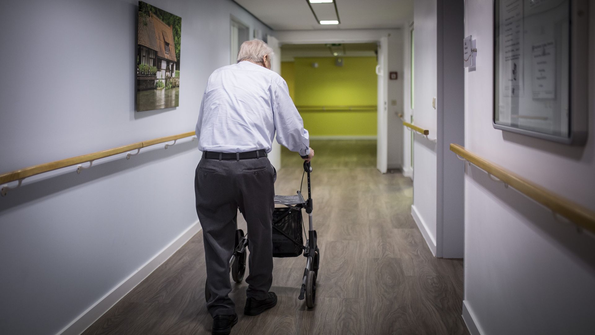 Old man with a walker walking away from camera