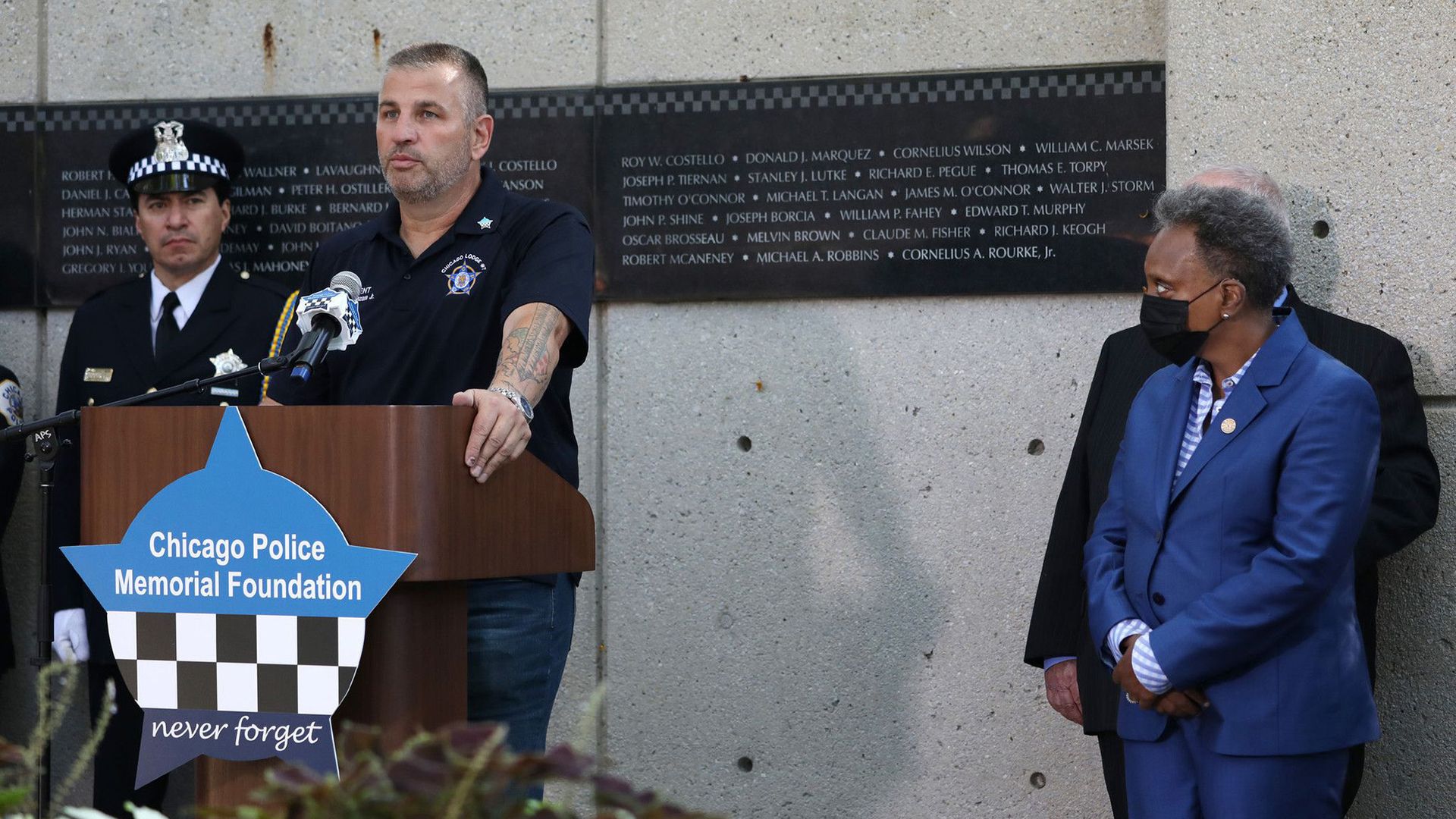 A man speaks on the podium while a woman stares at him.