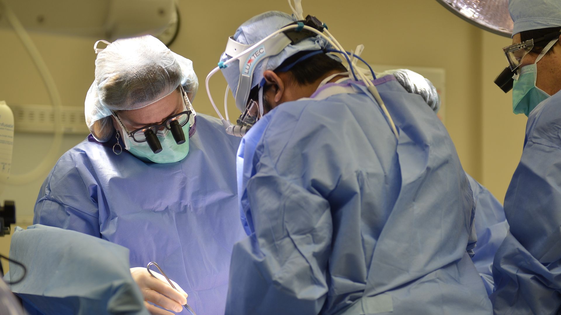 Surgeons hover over an operating table with surgical instruments.