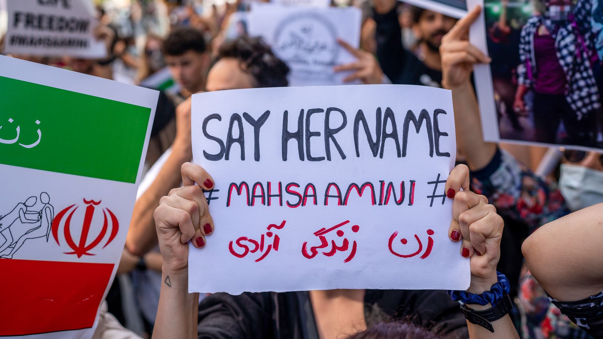 Protester holding a sign reading "Say her name: Mahsa Amini"