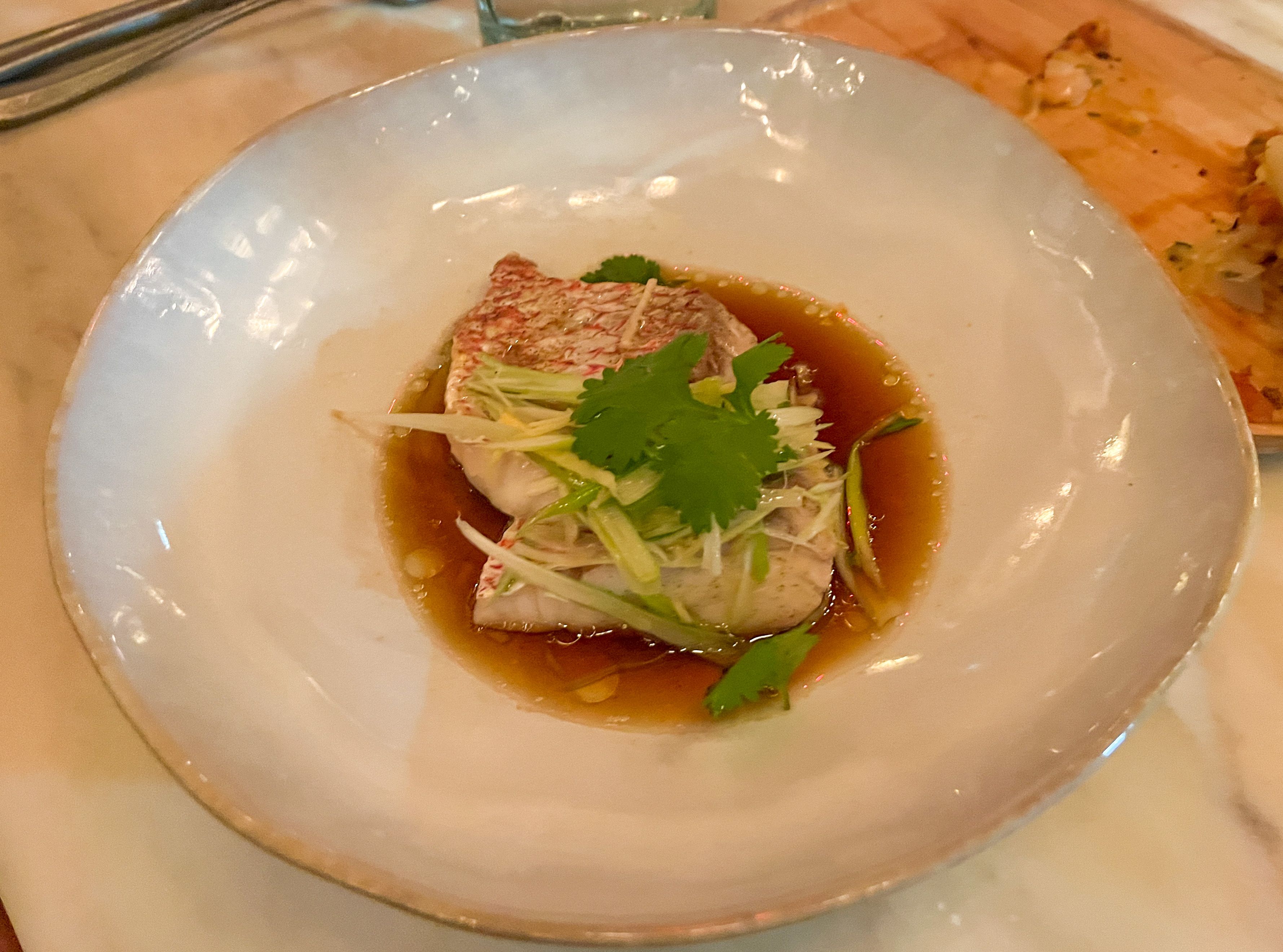 Steamed red snapper served on a white plate.