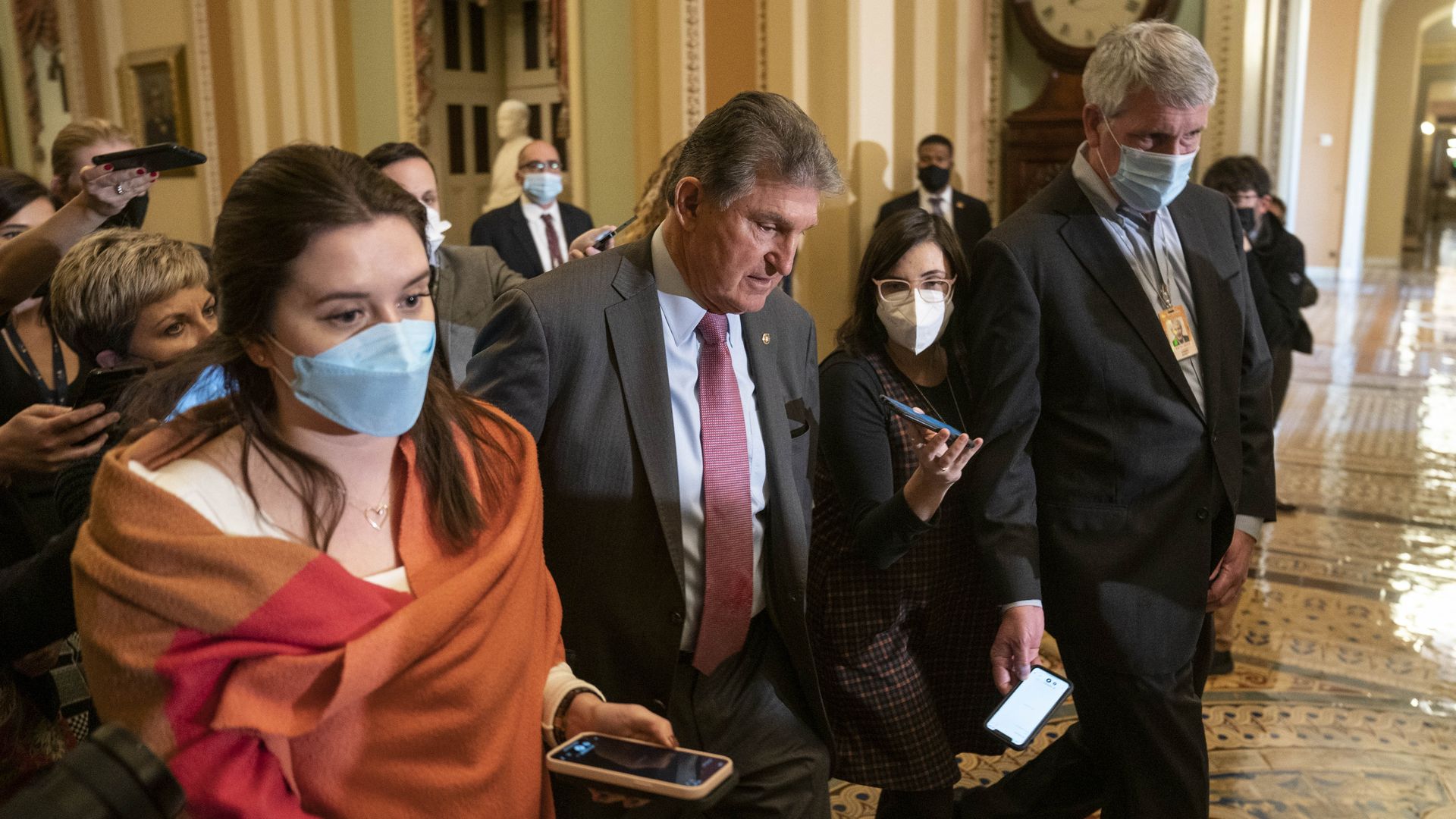Sen. Joe Manchin is seen being trailed by reporters as he walks through the Capitol on Tuesday.
