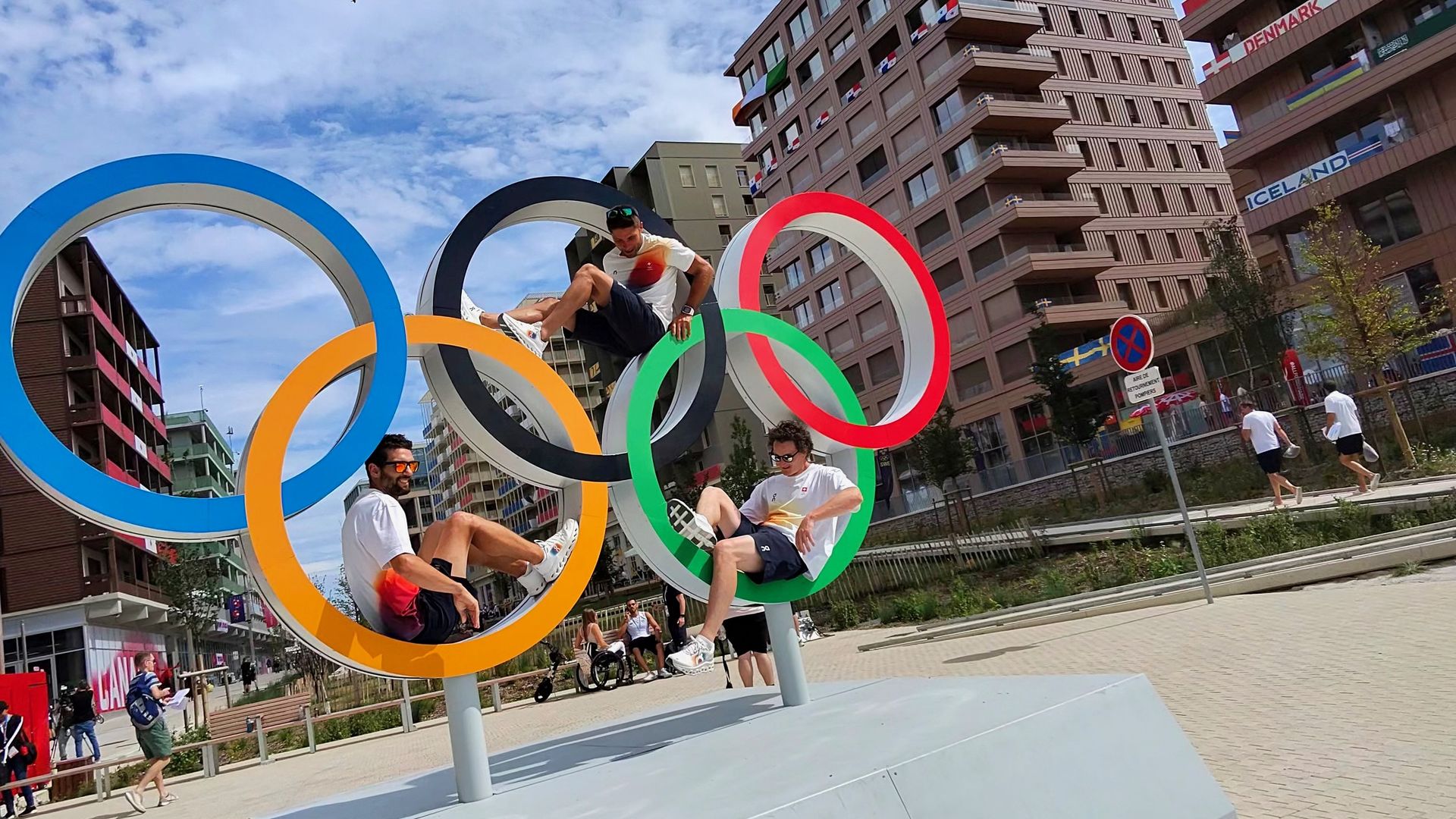 Athletes pose inside giant Olympic Rings located within the Olympic Village