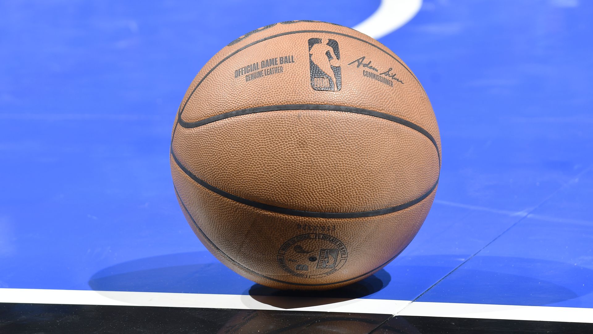 An official NBA basketball sits on a blue court.