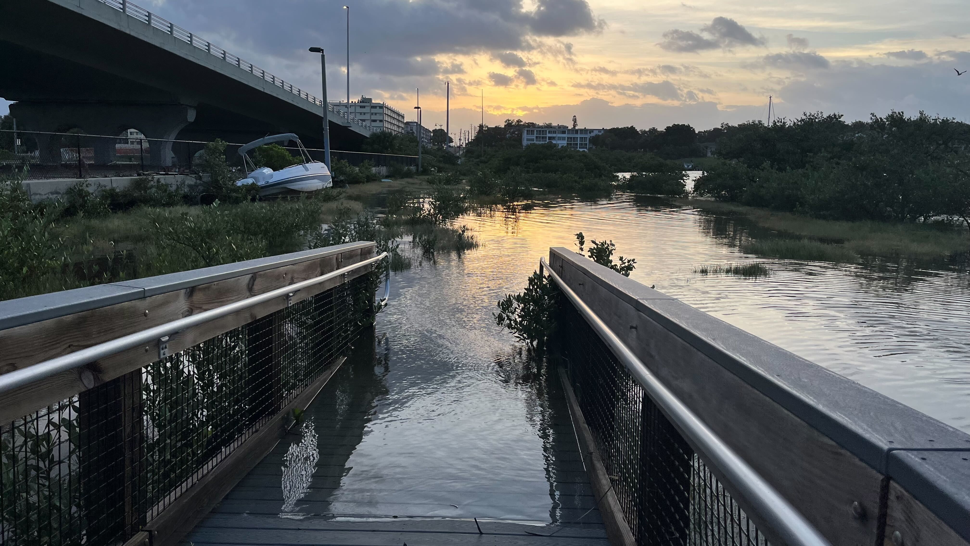 Water covering a ramp and a white pleasure boat washed ashore under the Belleaire Causeway