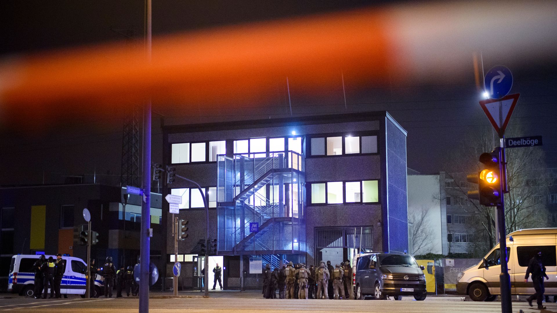 Photo of law enforcement officers gathered outside a building that has been cordoned off with red police tape