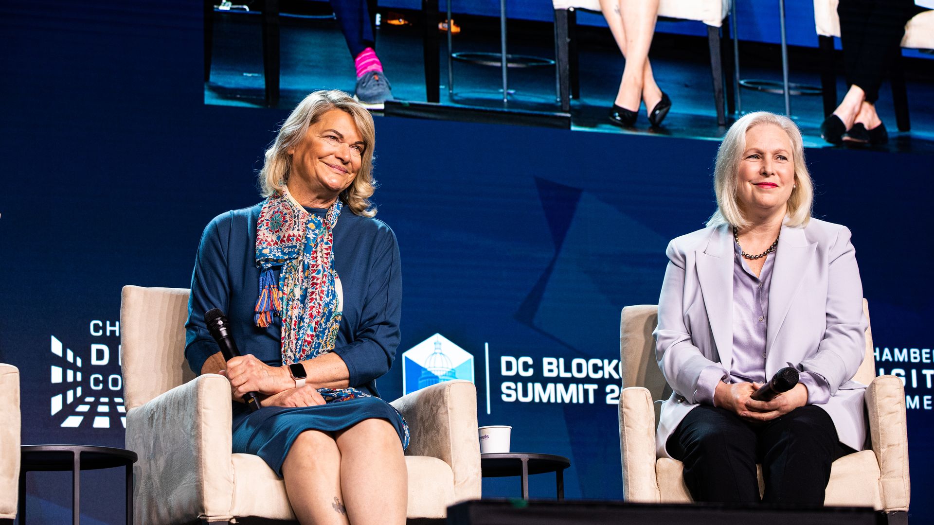 Senators Cynthia Lummis and Kirsten Gillibrand sit together on stage