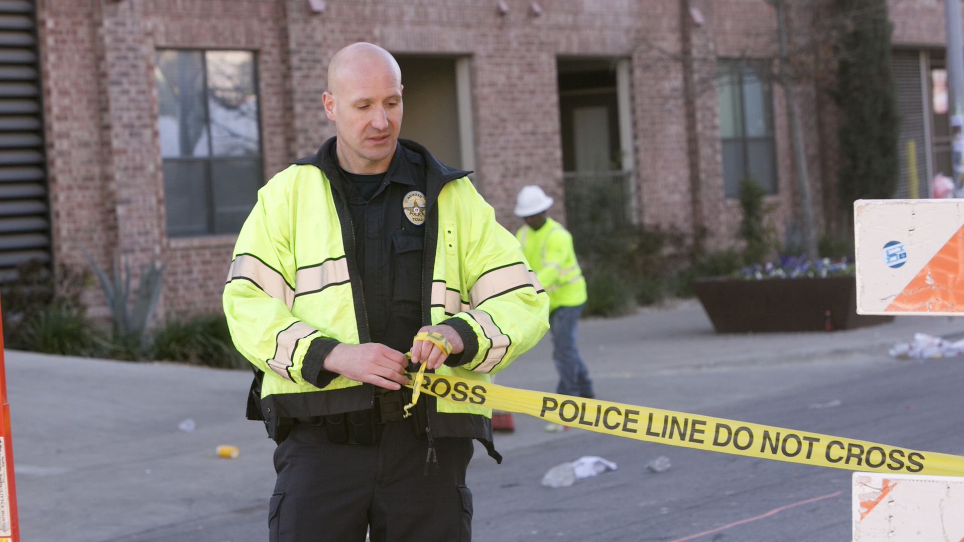 A police officer unwinds tape that reads "police line do not cross"
