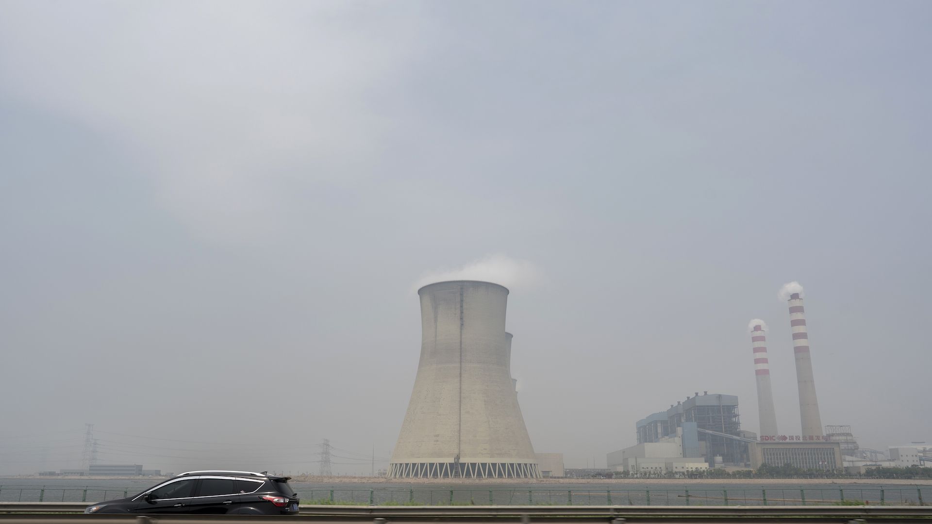 A huge thermal power plant is emitting vapor into the sky, seen from the highway from Tianjin to Beijing. 