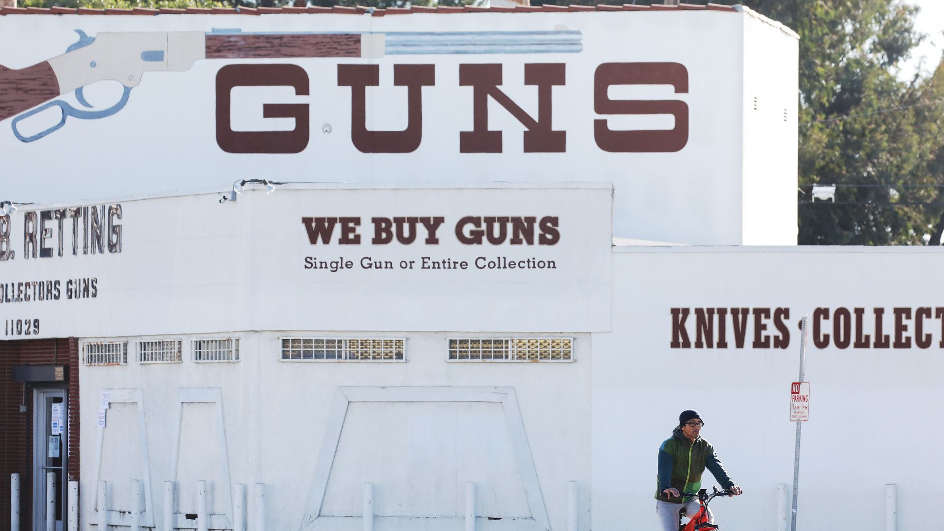 A cyclist rides past the Martin B. Retting, Inc. guns store