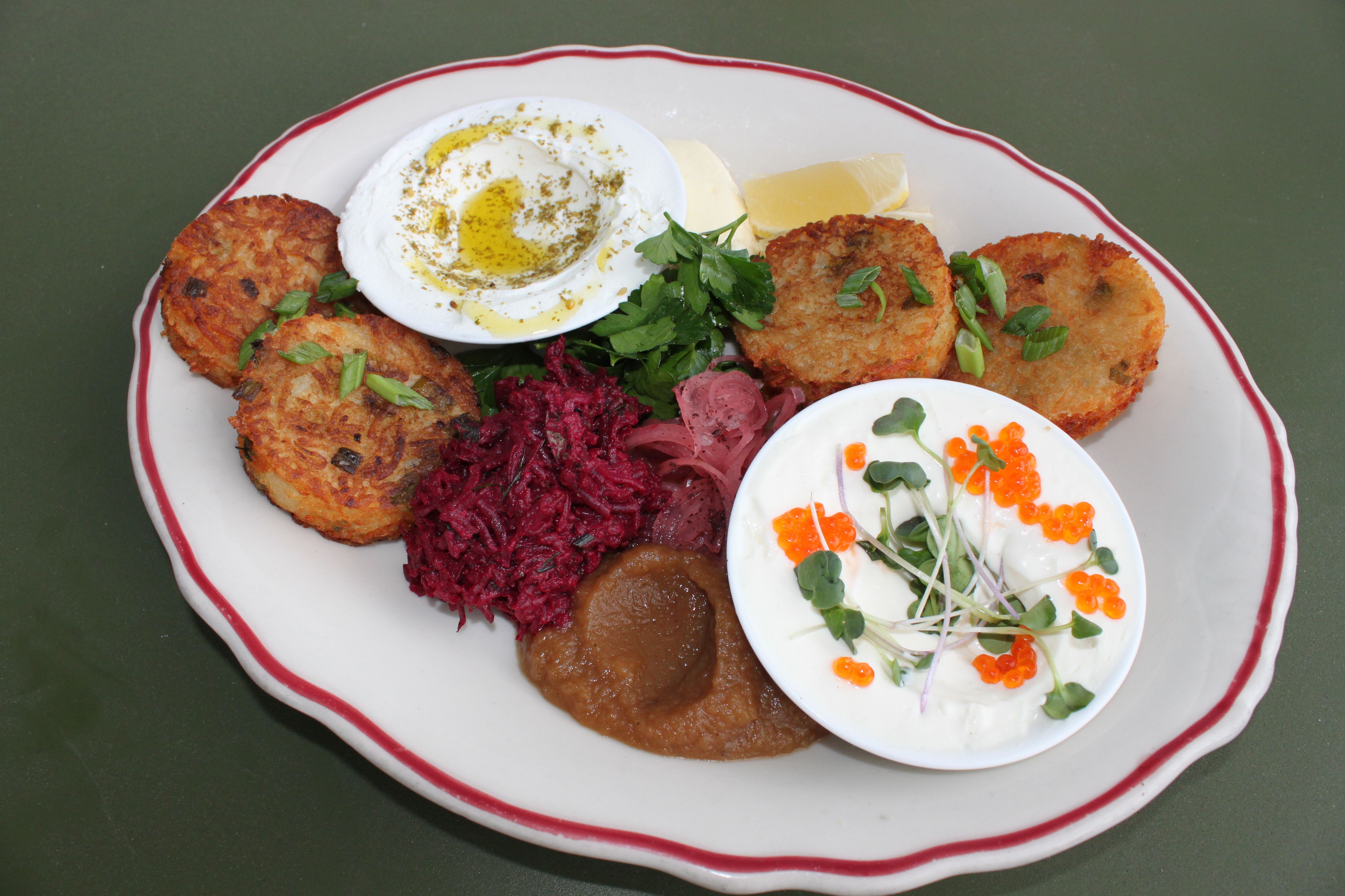 A close-up photo of a plate with latkes and various toppings.
