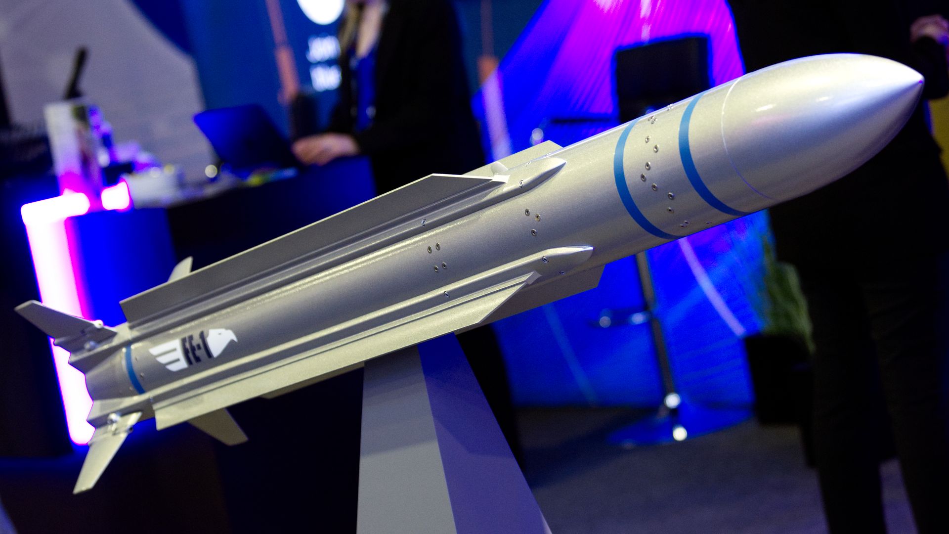 A BlueHalo-made missile is perched at the company's booth. The background is neon blue and purple.