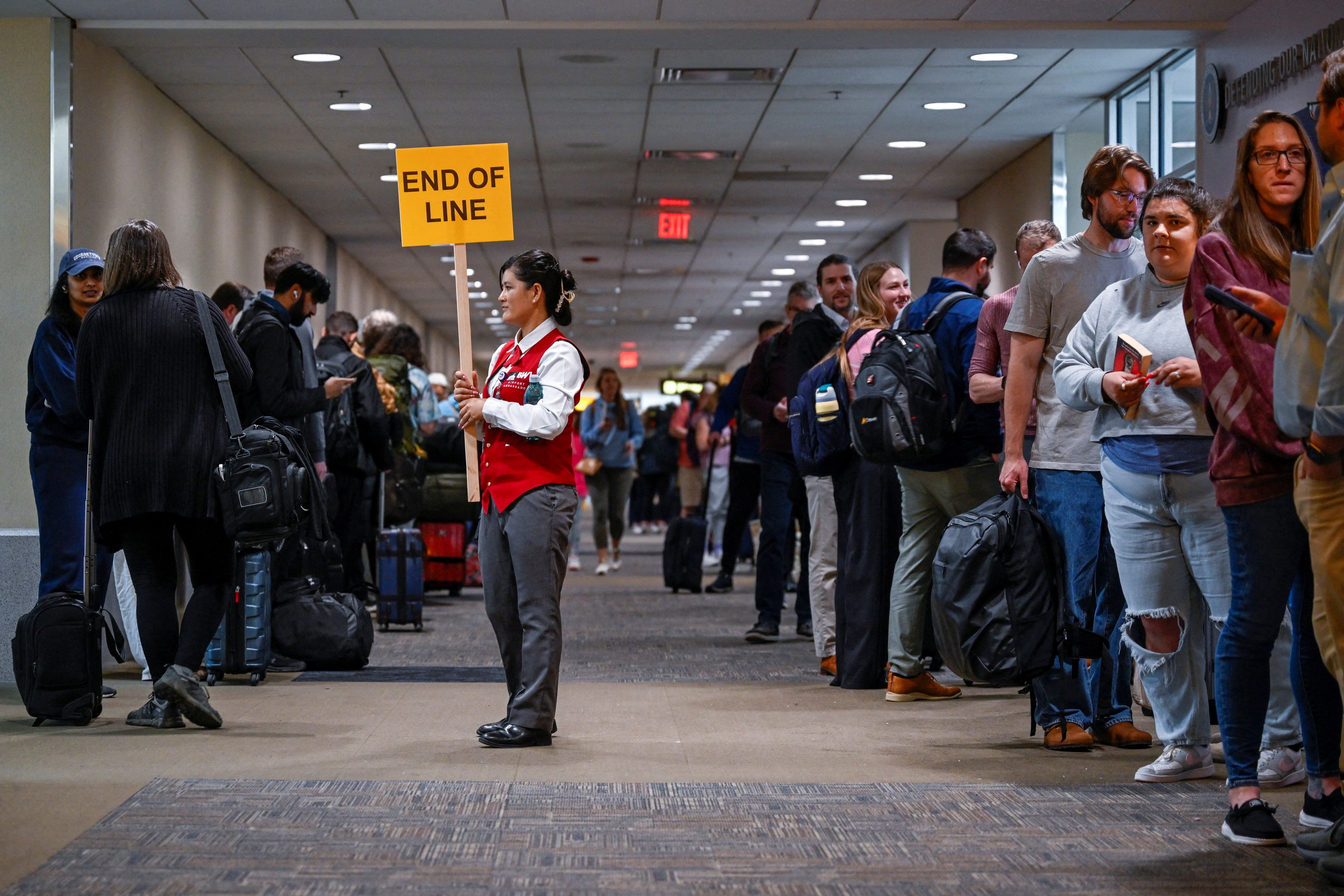 An airport employee holds a sign indicating the end of the line after the U.S. Senate voted to end a partial government shutdown that has caused severe ‌delays at airports across the country, at Baltimore/Washington International Thurgood Marshall Airport (BWI), in Baltimore, Maryland, U.S., March 2