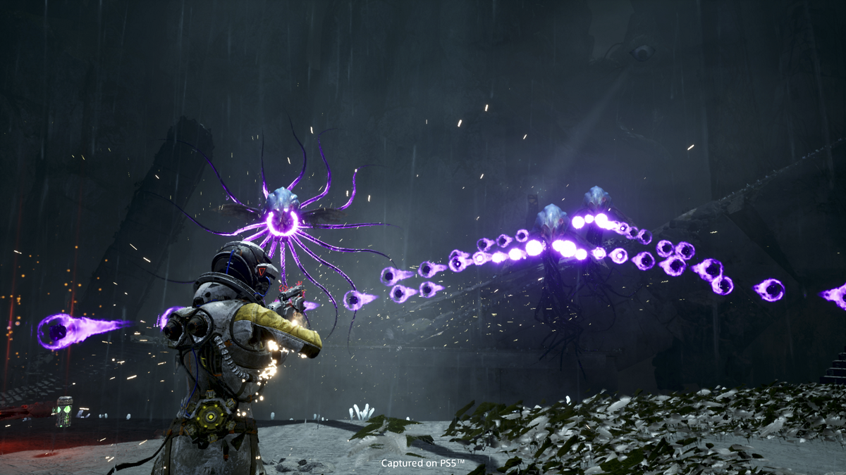 Video game screenshot of an astronaut in a yellow suit aiming a gun at an alien creature that is spitting purple energy blasts