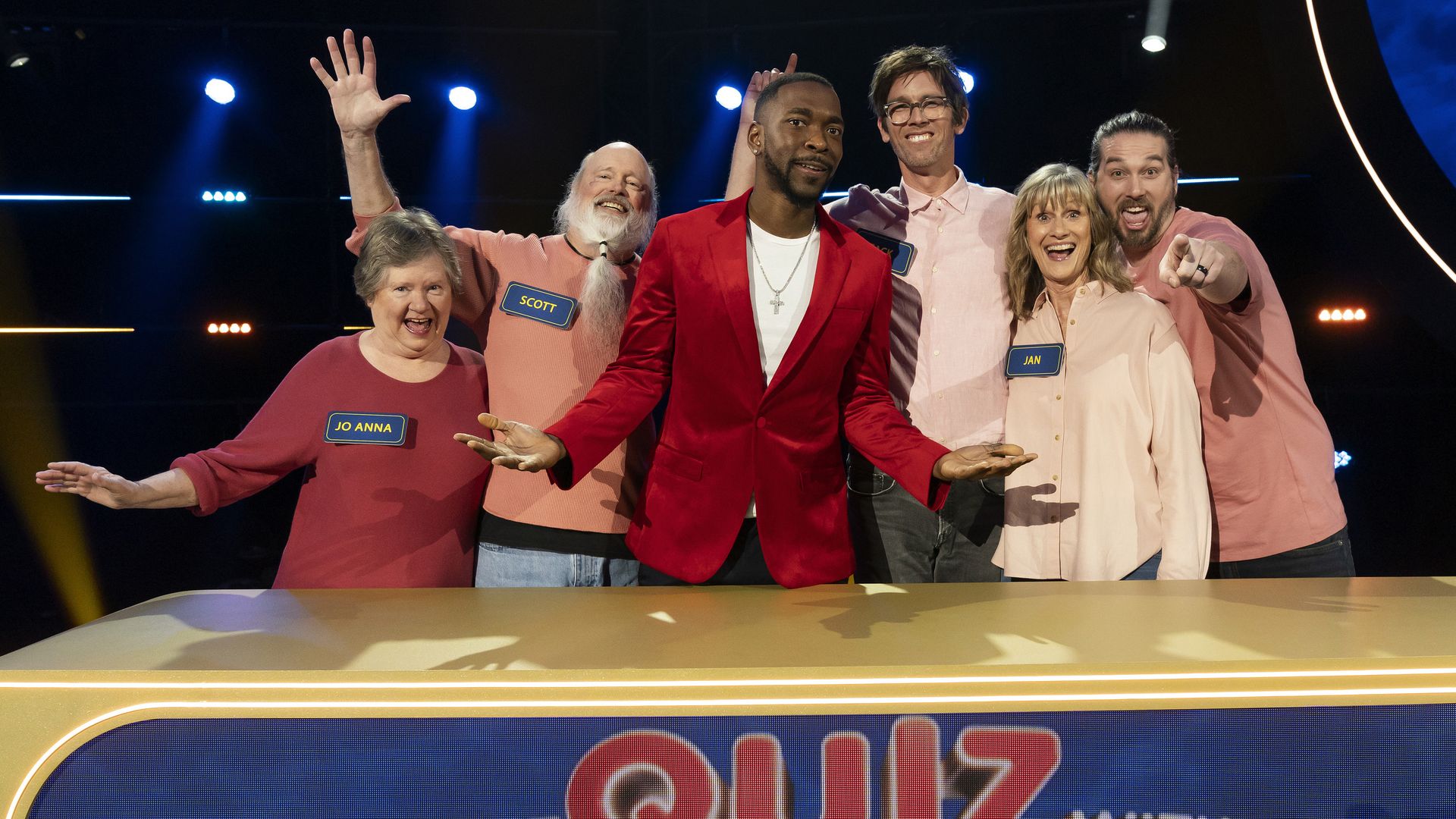 six people point at the camera on a TV gameshow set
