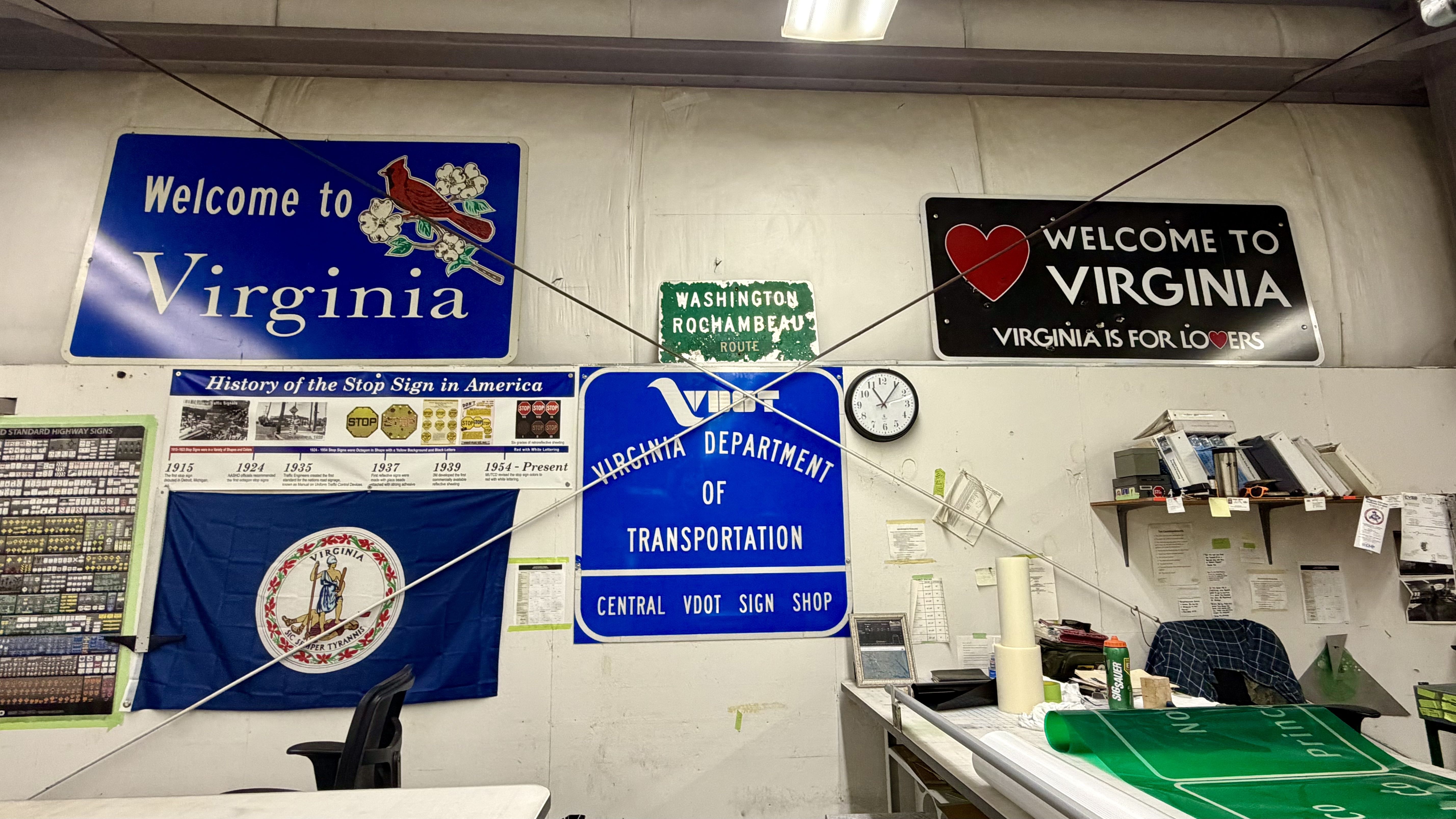 Indoor wall with Virginia signs: a large blue Welcome to Virginia on the left, a black Welcome to Virginia with a heart on the right, and a green Washington Rochambeau Route plaque.
