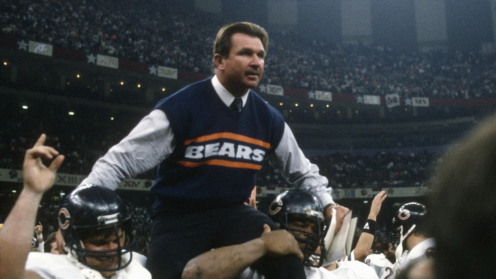 Photo of a man in a sweater that says "Bears" getting lifted by teammates on shoulders