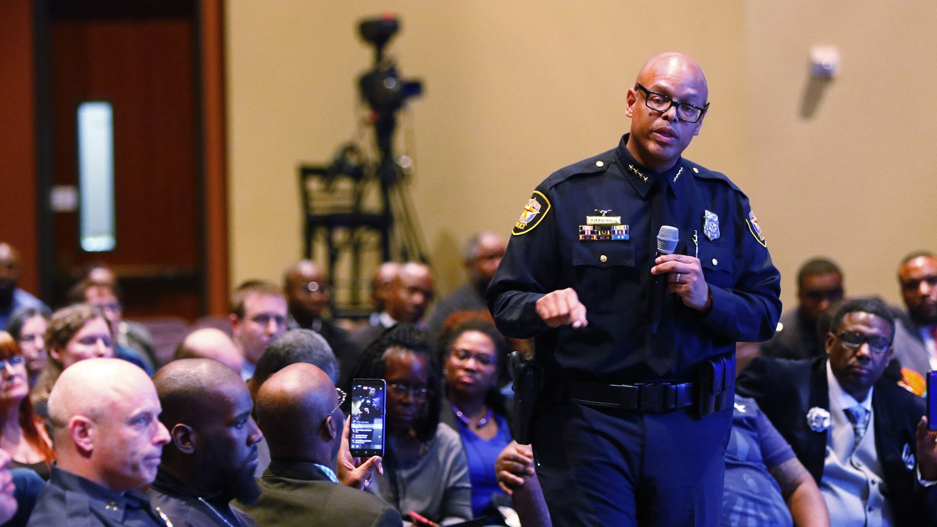 A man in a police uniform speaks to an audience