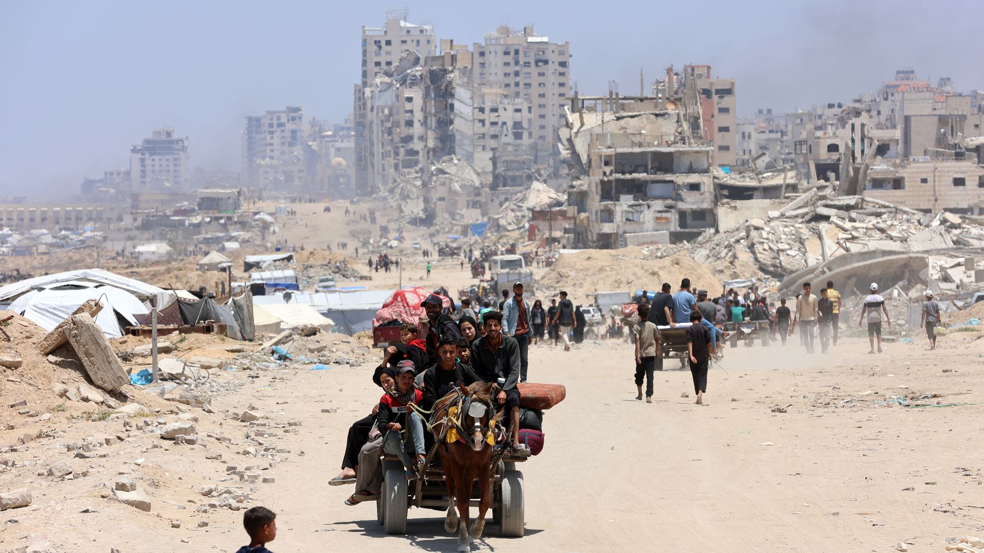 family on motorbike with luggae amid rubble