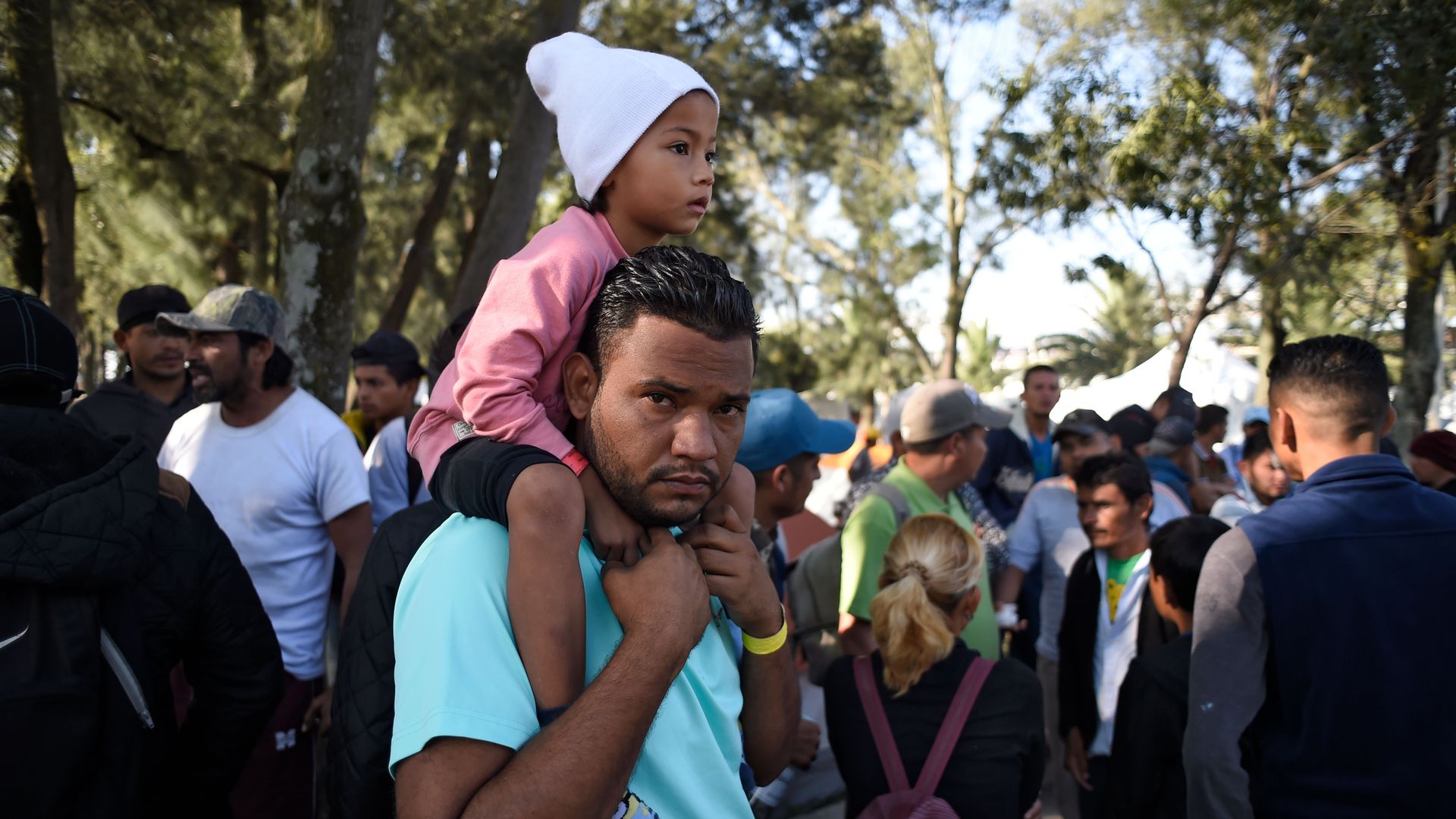 A migrant child sits on her father's shoulder 
