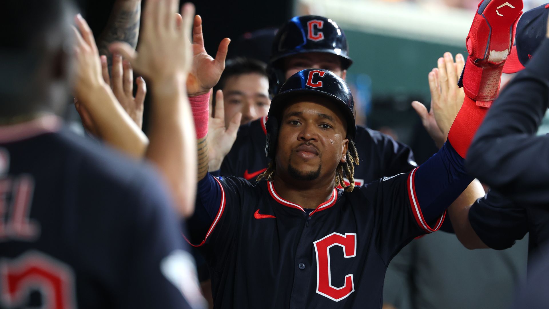 Guardians' Jose Ramirez in helmet and blue jersey giving high fives in dugout