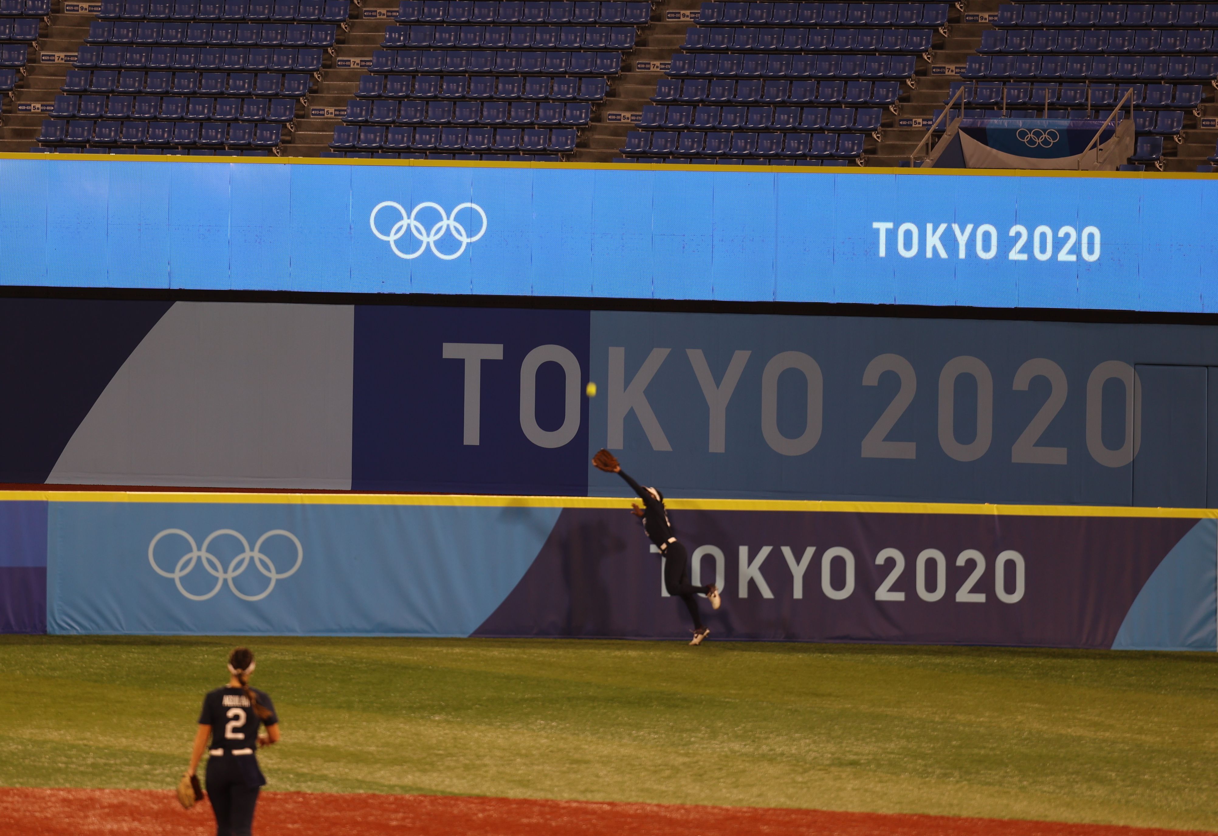 Outfielder Janie Reed leaps over the fence to steal a sure home run from Team Japan in the sixth inning of Tuesday's gold medal game. Photo: Ina Fried/Axios