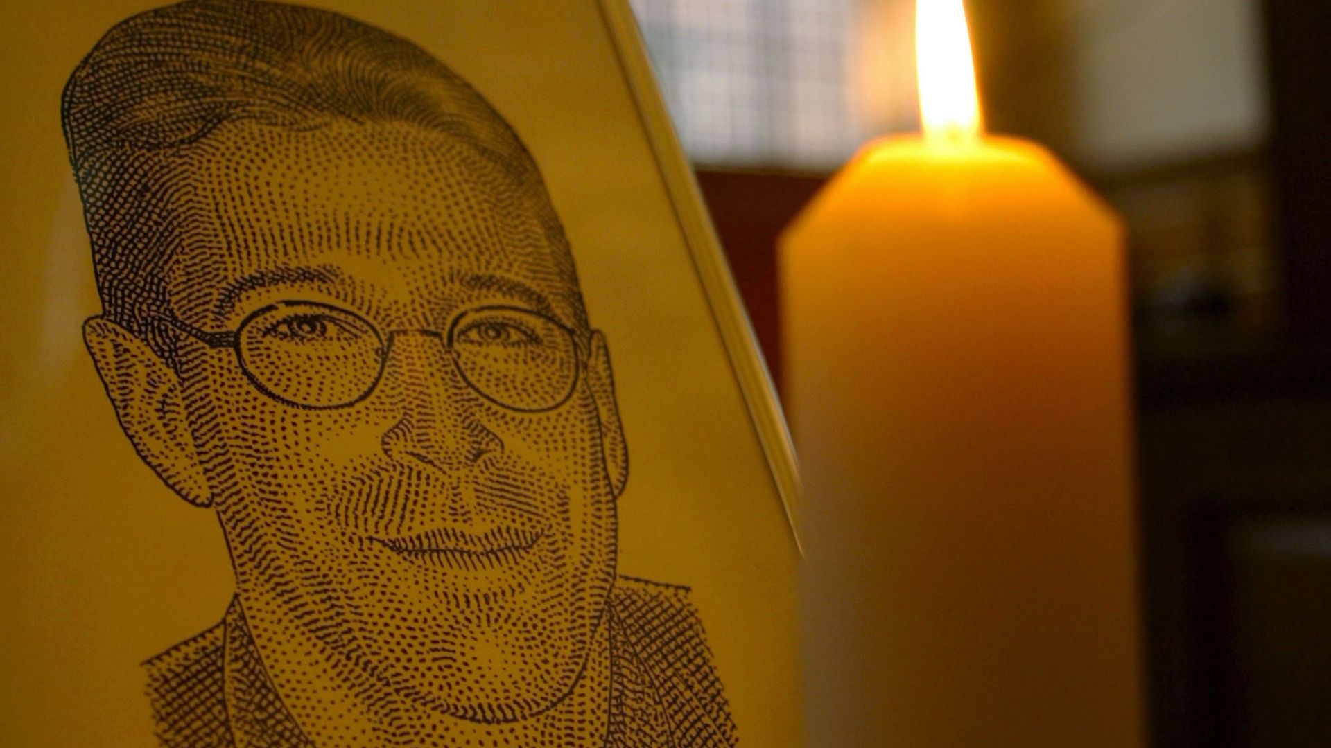  A candle flickers next to a portrait of Wall Street Journal reporter Daniel Pearl March 5, 2002 