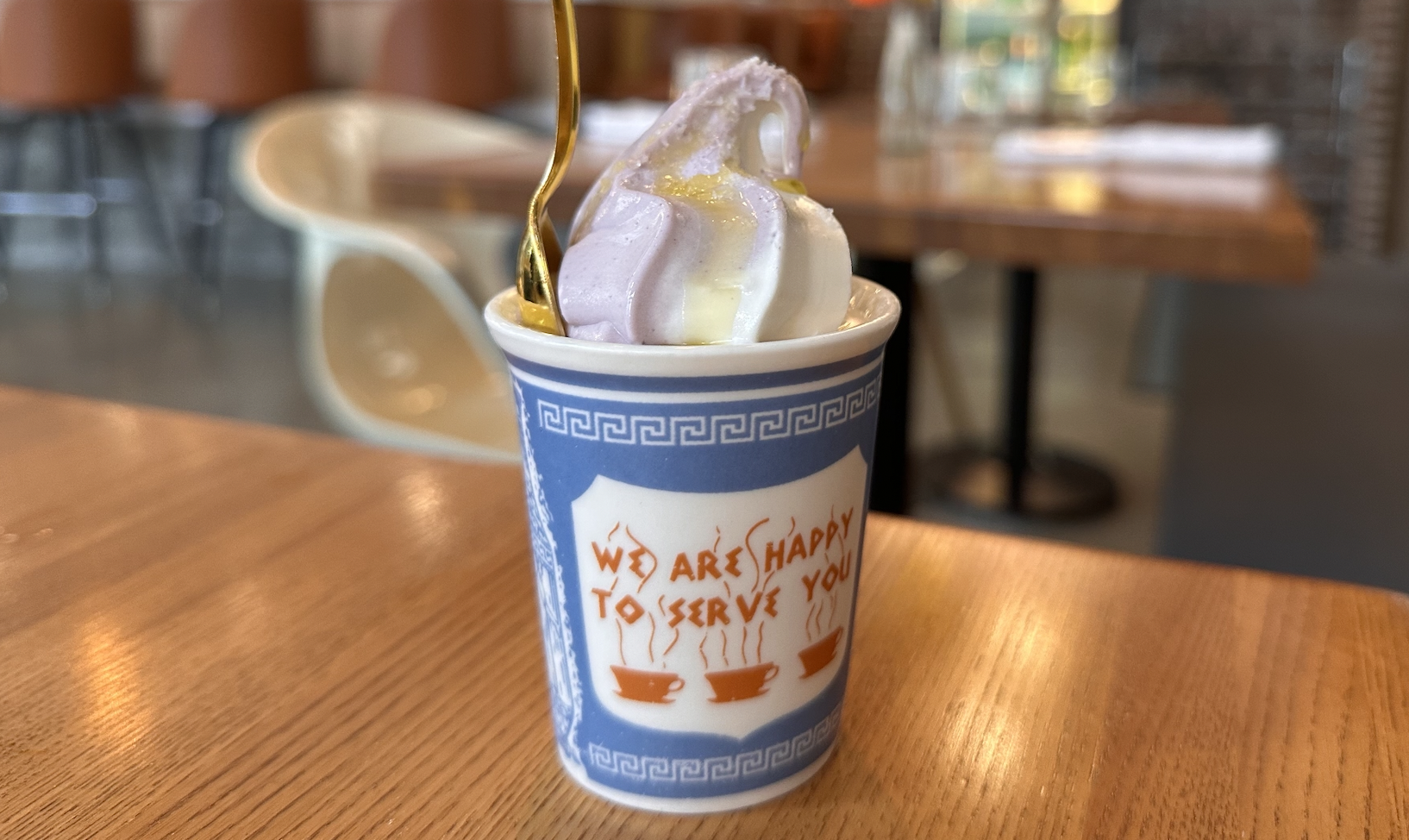 Blue and white swirls of frozen yogurt in a ceramic cup that says "We are happy to serve you"