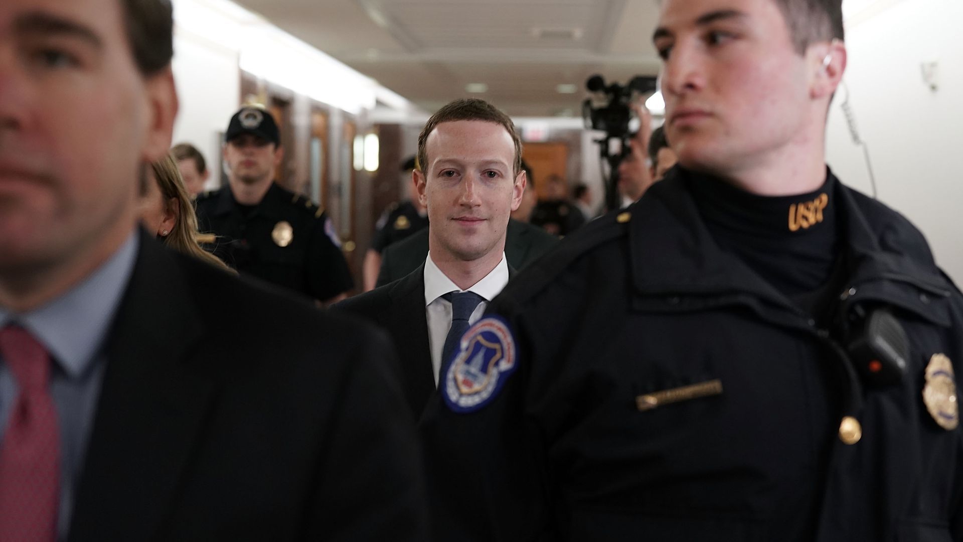 Zuckerberg behind two security guards