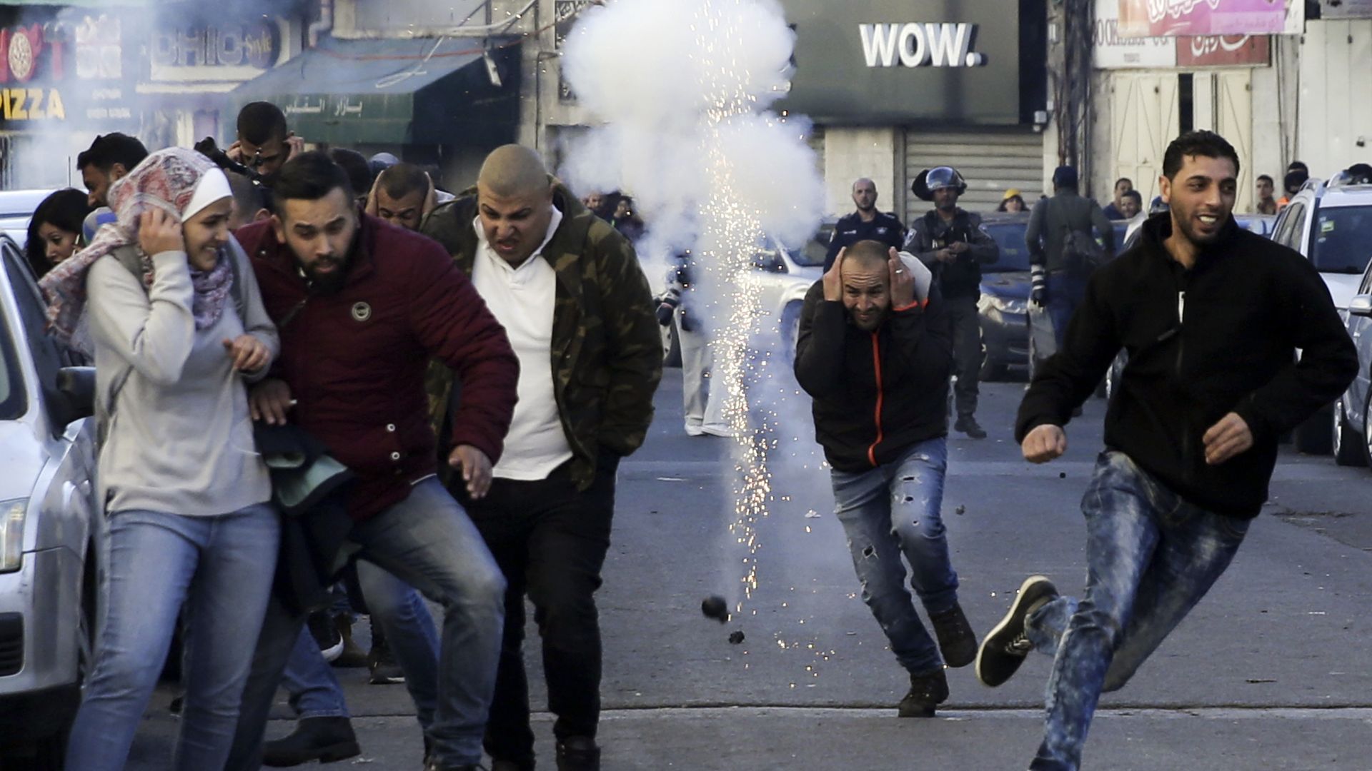 Palestinians run away from a sound bomb during clashes with Israeli security forces.