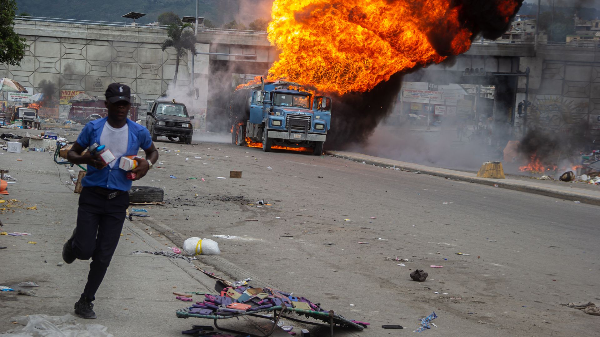 A man evacuates due to the fire during a tanker carrying diesel exploded after being hit by projectiles fired by armed men trying to apprehend the truck in Port-au-Prince, Haiti, Tuesday June 04