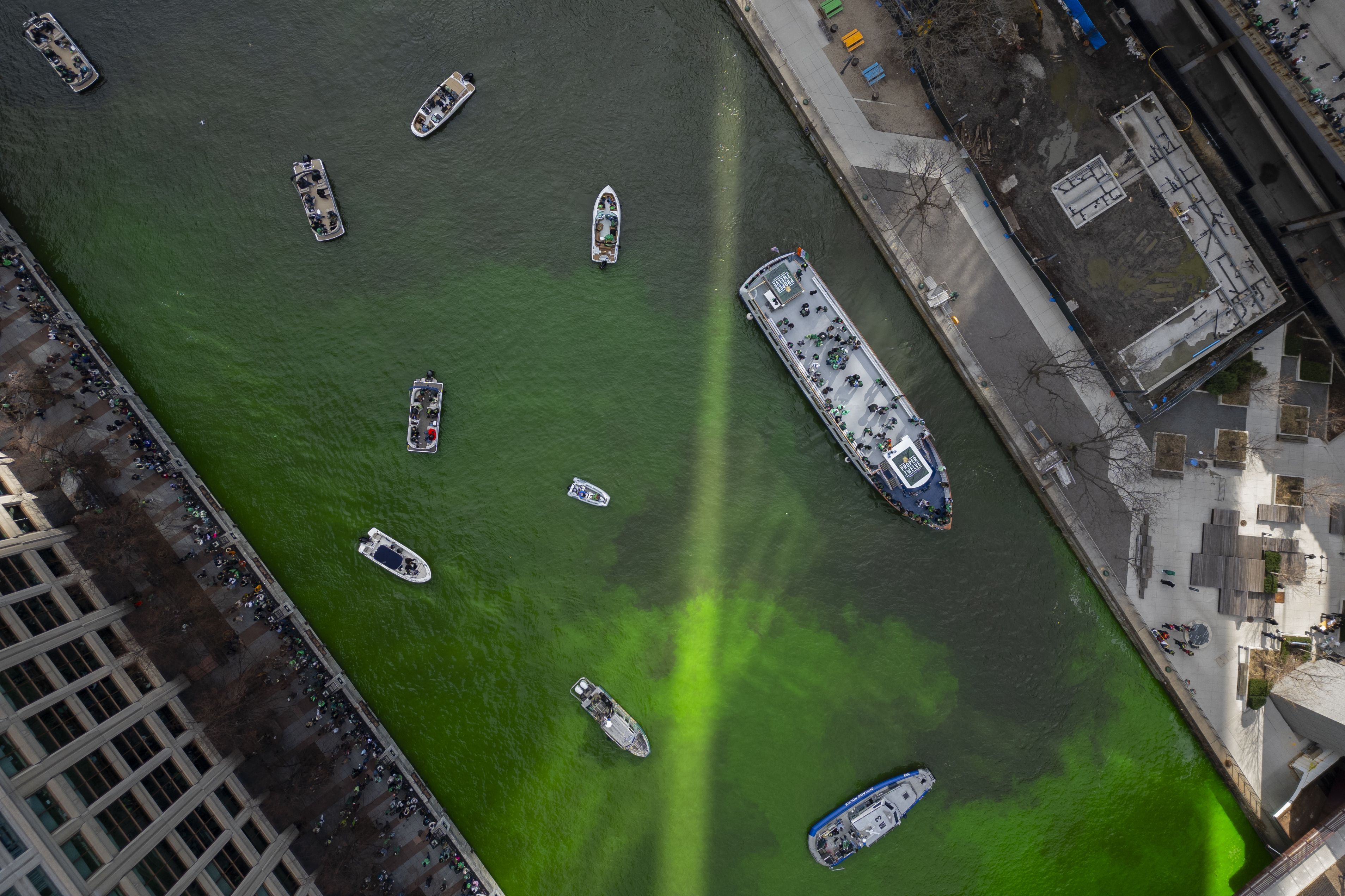 Boats of various sizes seen on the Chicago River — which is dyed green — from an aerial view