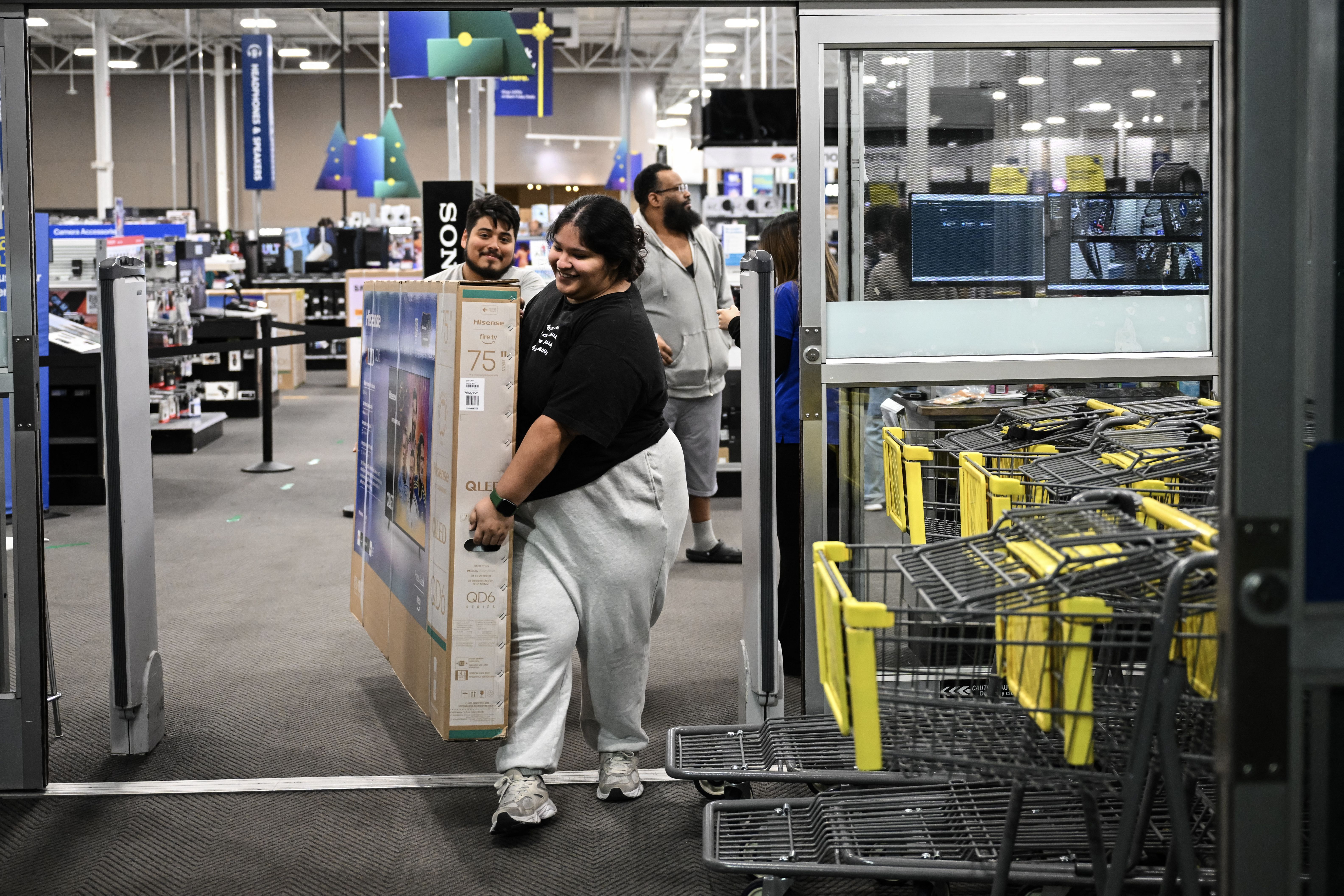 People exit Best Buy with a brand new television on Black Friday, in Houston, Texas, on November 28, 2025. The store opened at 6am to allow shoppers to get special deals on goods for the holiday season. (Photo by RONALDO SCHEMIDT / AFP via Getty Images)
