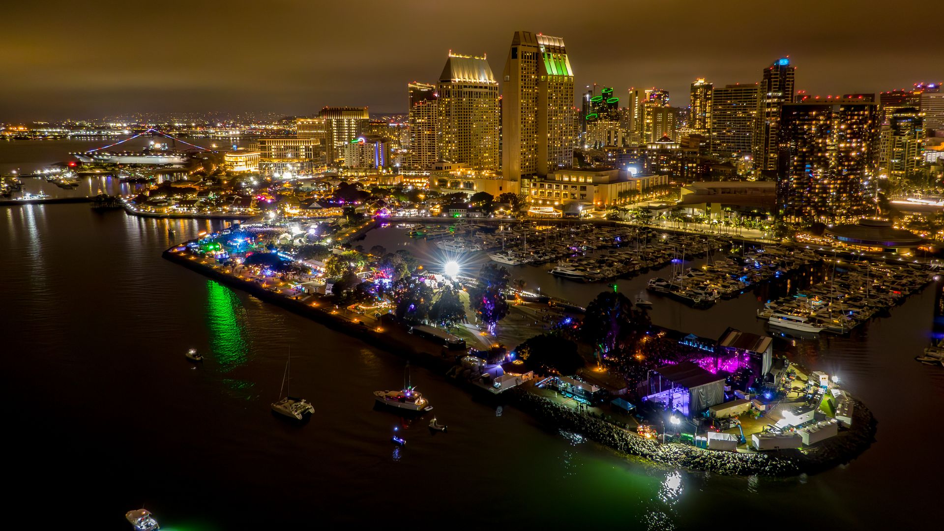 An overhead view of the festival at night on the Embarcadero North with the San Diego downtown skyline behind it