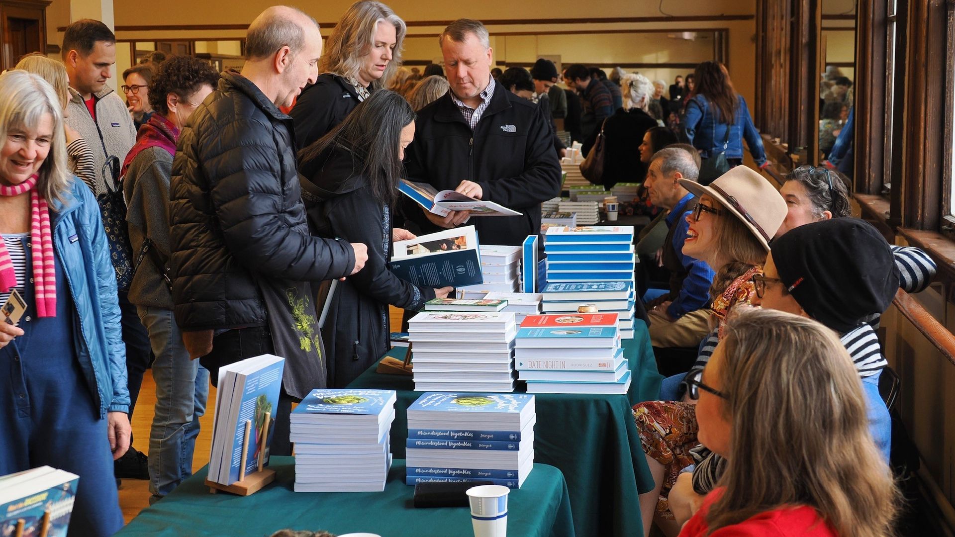 Authors sit behind a table as readers line up to talk. 