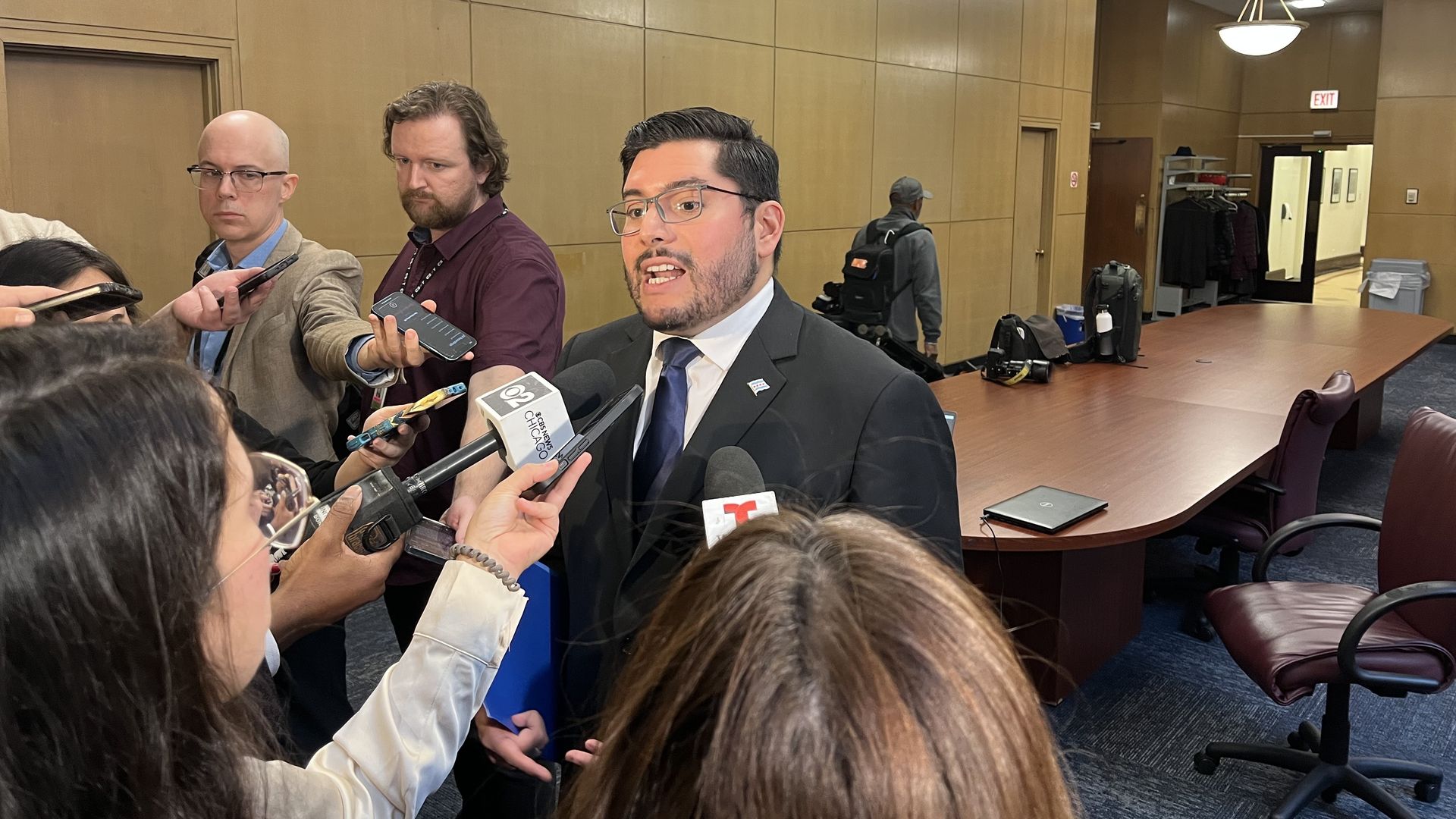 Photo of a man talking to reporters holding microphones