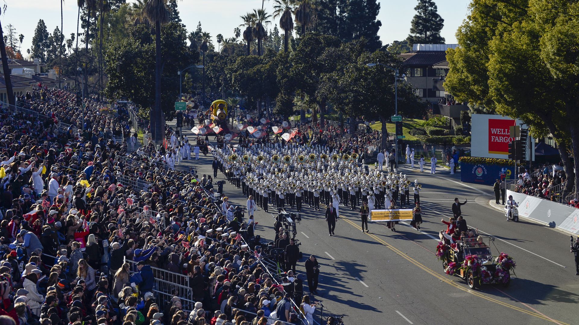People in the stands watching a marching band perform at the Rose Bowl Parade in Pasadena