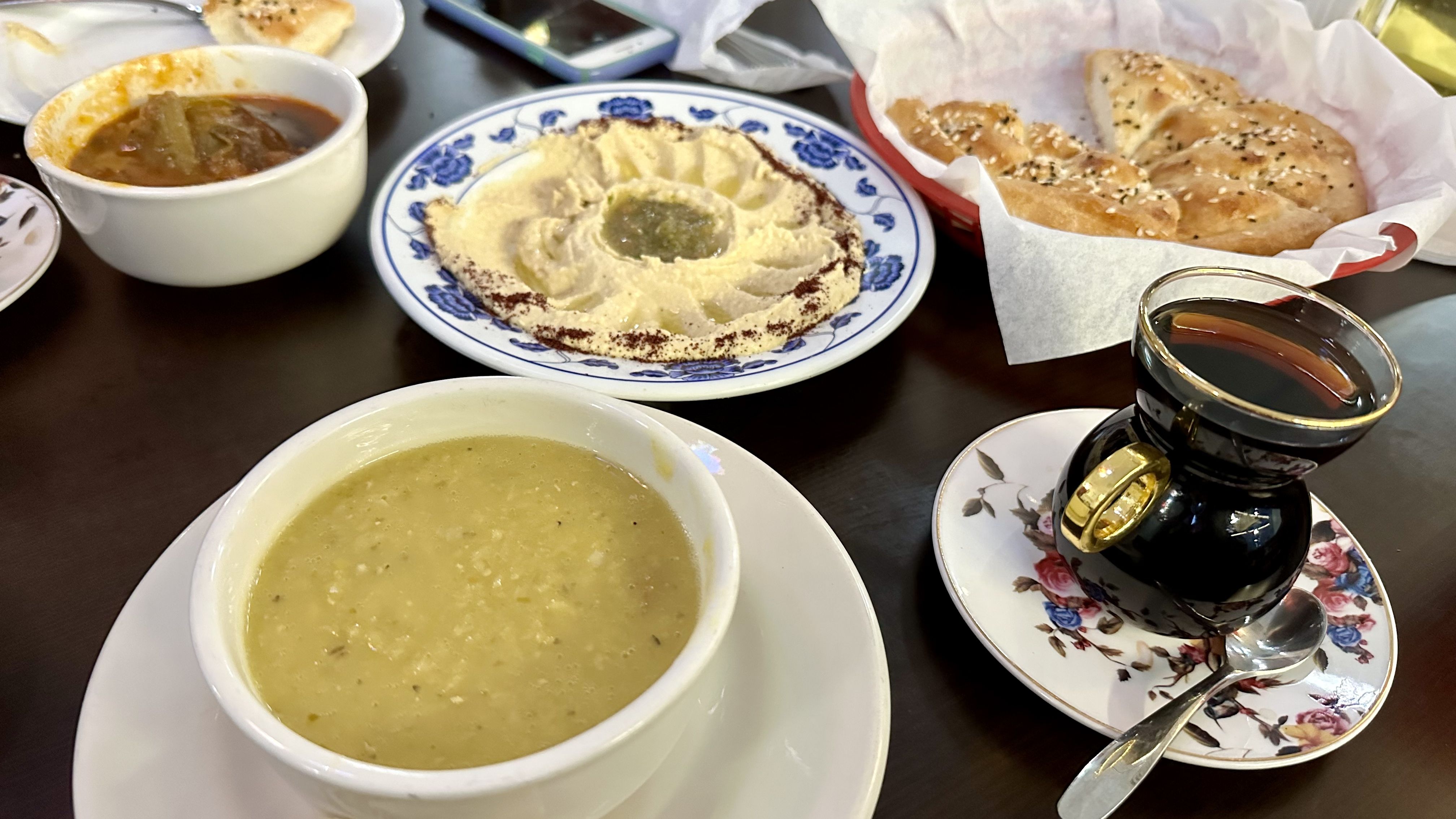 Photo shows lentil soup, hummus, black tea, fresh bread and eggplant soup.