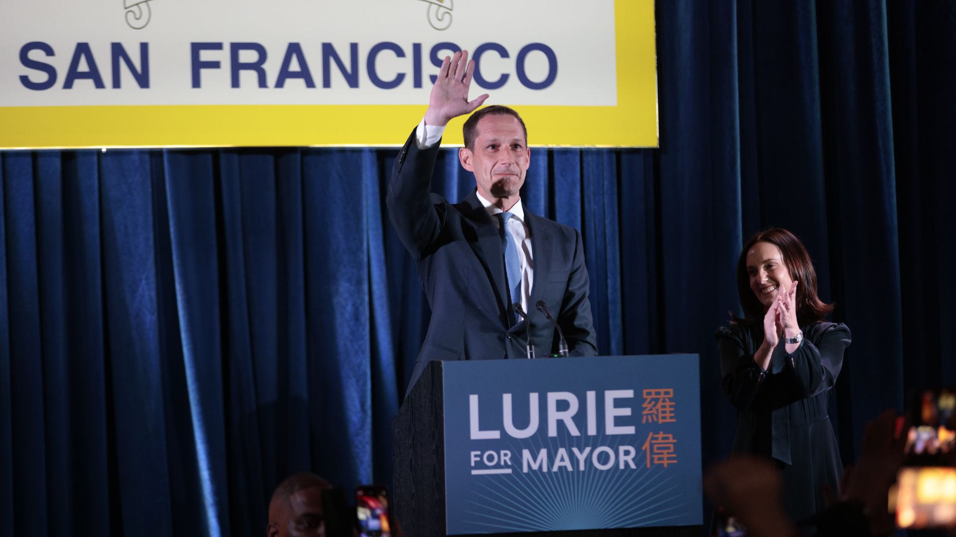 A man in a suit waves