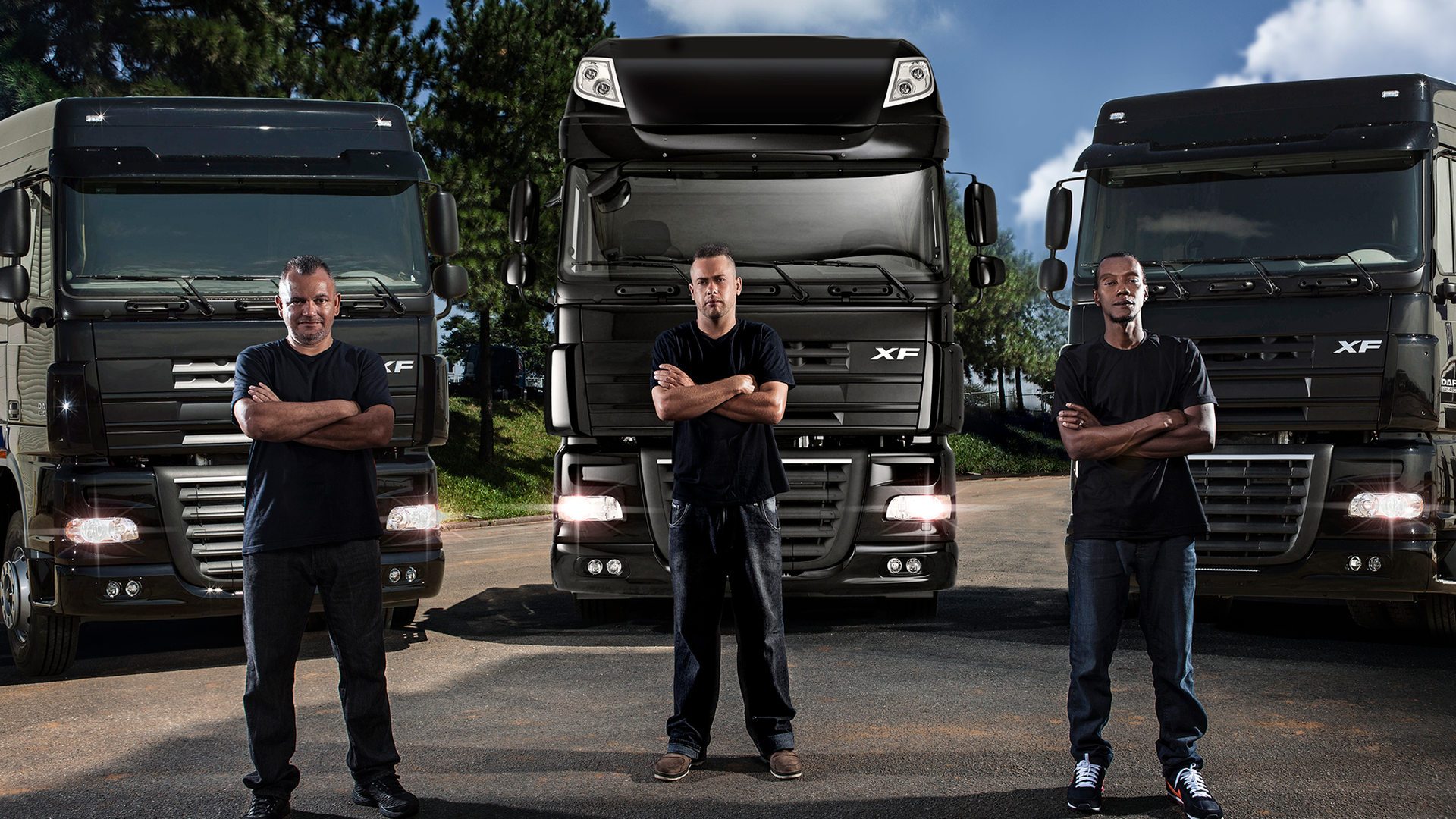 Three men stand in front of their trucks.