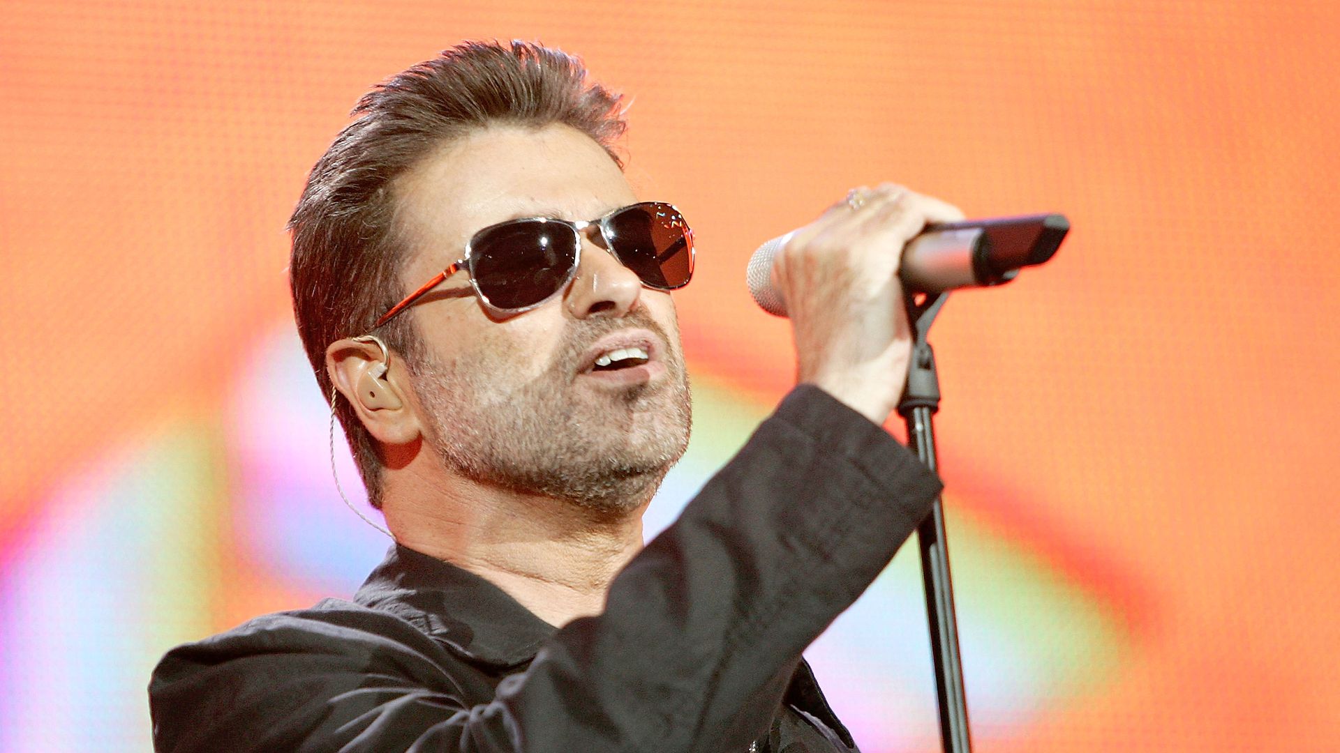 George Michael sings into a microphone.