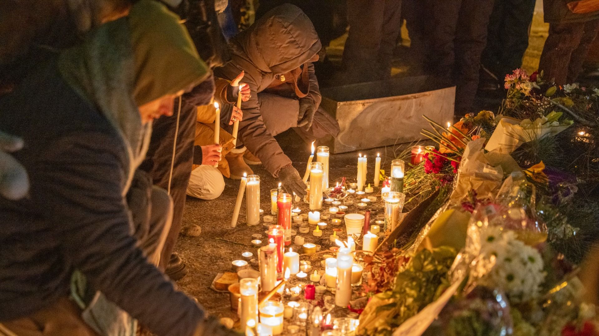 People put candles at a vigil.