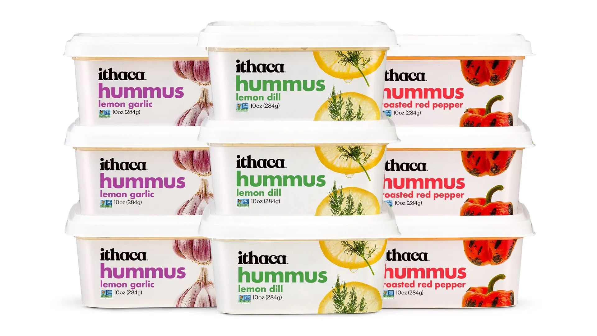 Tubs of hummus sit in front of a white background.