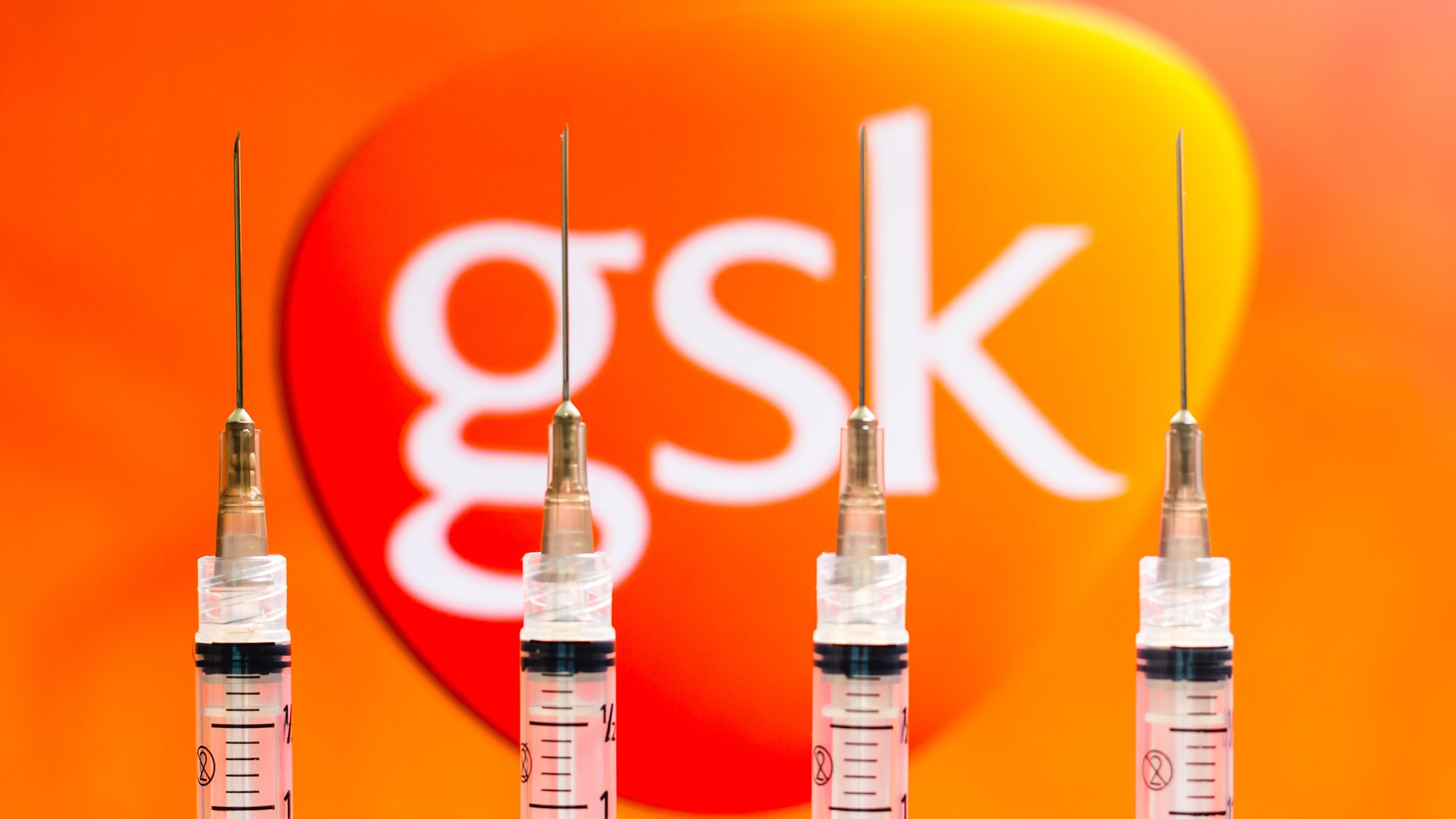 Picture of four vaccine syringes in front of the GlaxoSmithKline logo