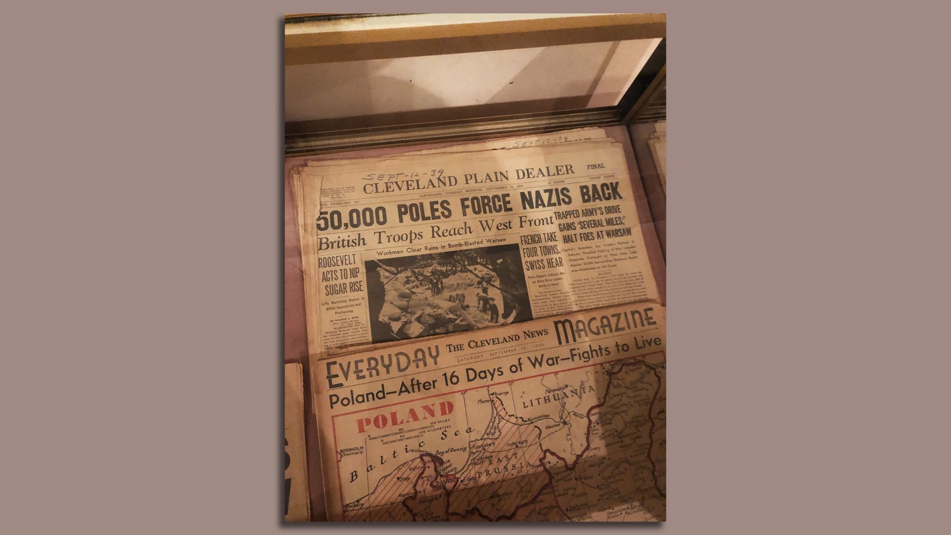 Cleveland newspapers from 1939 -- "50,000 POLES FORCE NAZIS BACK" -- in a glass case. 