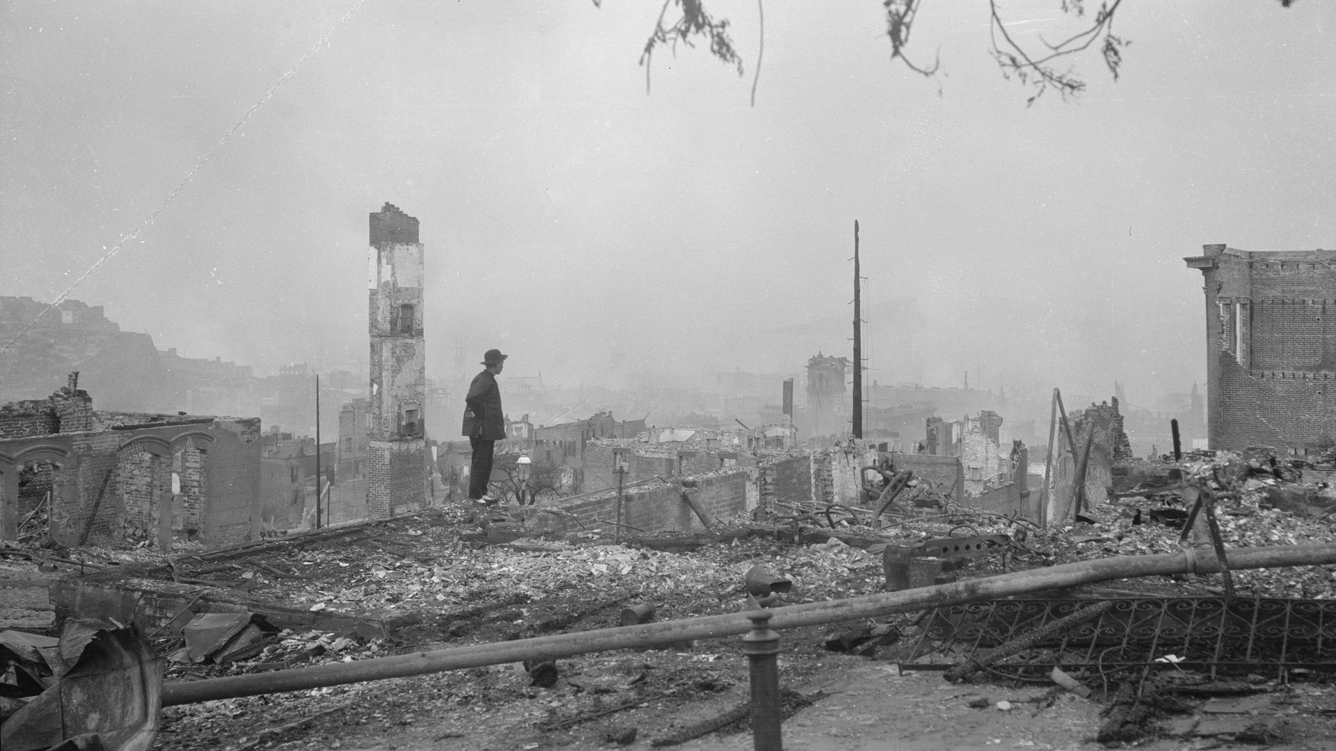 Photo of a person standing in rubble in the aftermath of an earthquake and fire