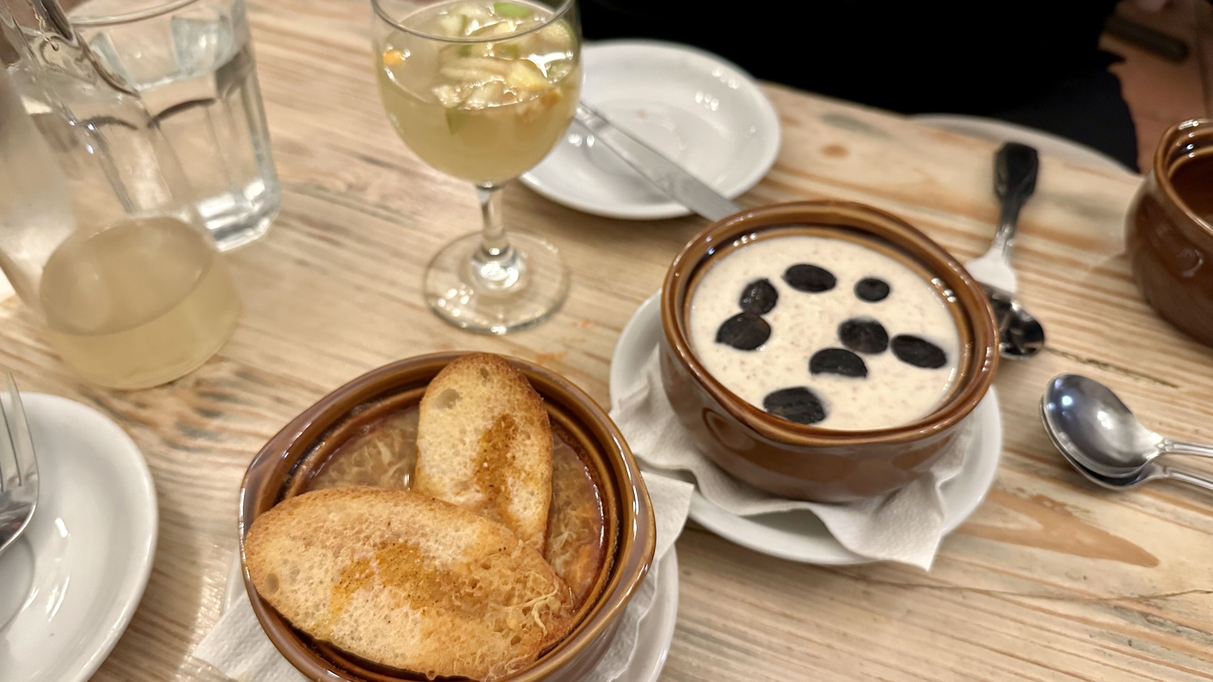 Photo shows two bowls of soup on a table with sangria