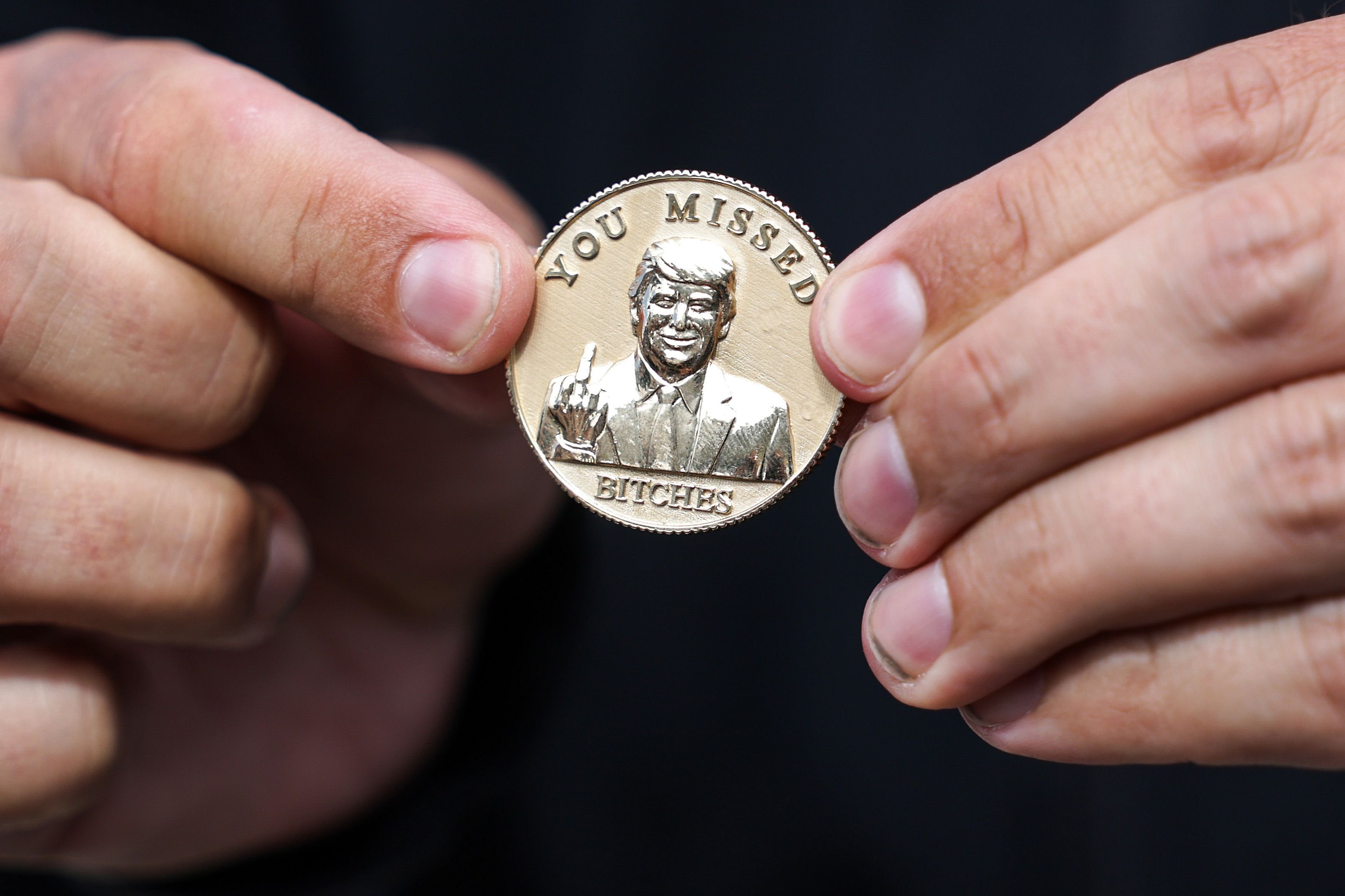 ) Florida Gov. Ron DeSantis holds a coin that he gifted to U.S. President Donald Trump reading "You Missed Bitches" as Trump arrives at Southwest Florida International Airport on October 23, 2026 in Fort Myers, Florida. President Trump is traveling to Florida to rally for local Republican candidates