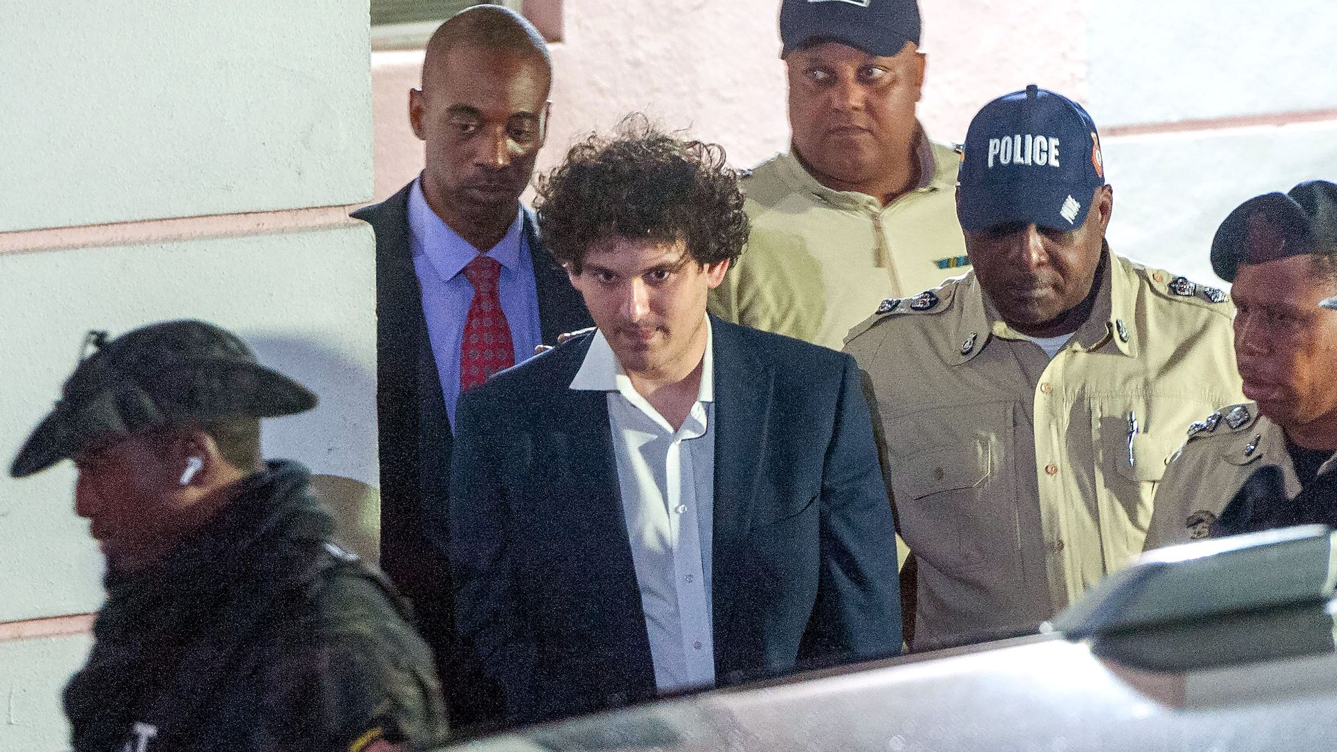FTX founder Sam Bankman-Fried (C) is led away handcuffed by officers of the Royal Bahamas Police Force in Nassau, Bahamas.