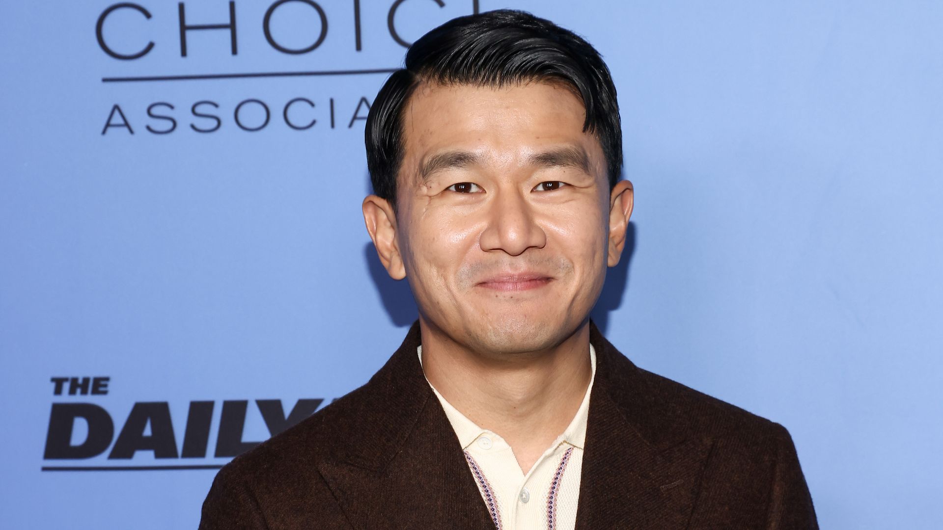 man of Asian descent smiling against a backdrop